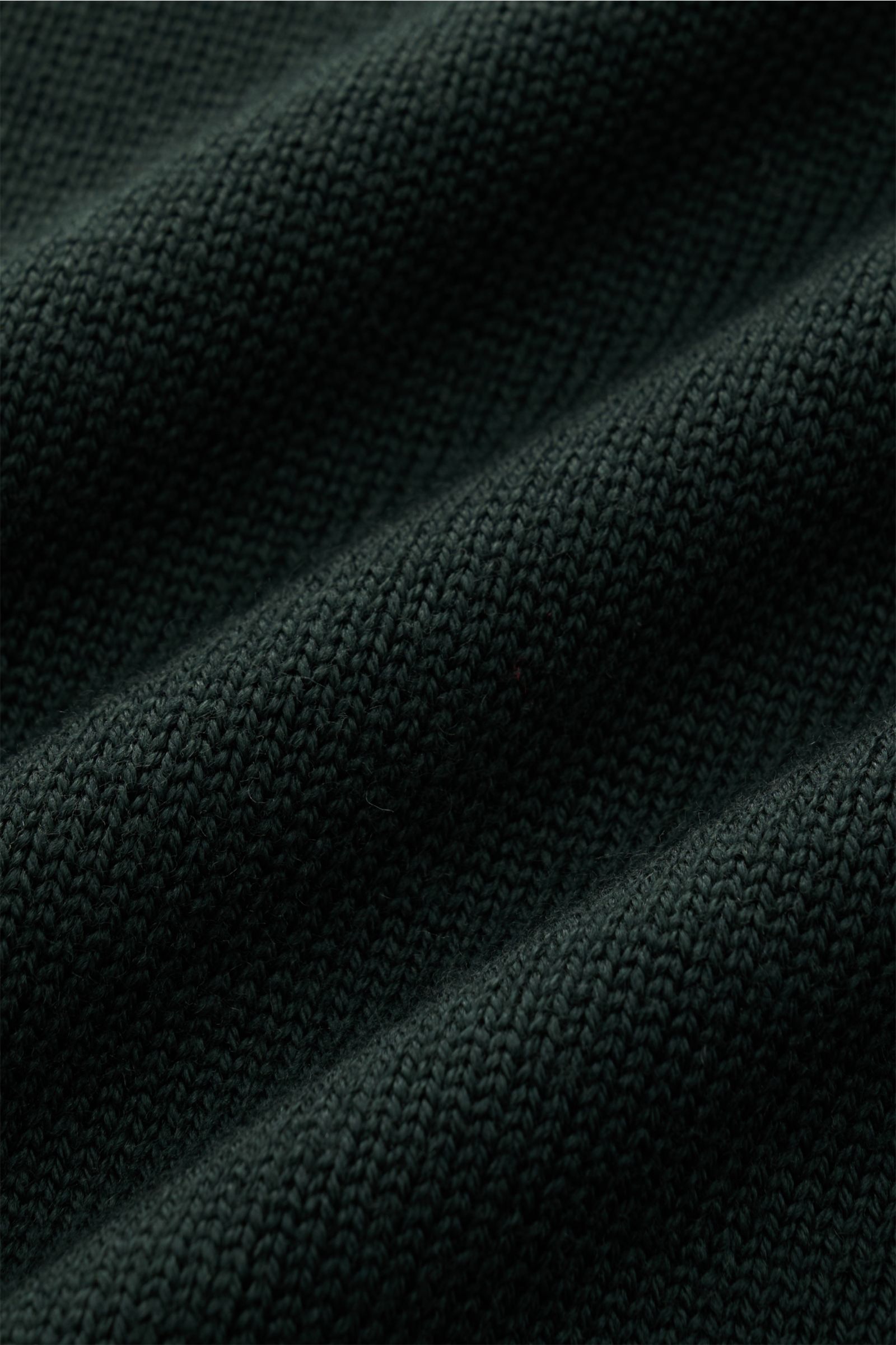 Nahaufnahme des dunkelgrünen B.F. Knitwear Merino Rollkragenpullovers mit mittelfeinem Strickbild aus reiner Merinowolle.