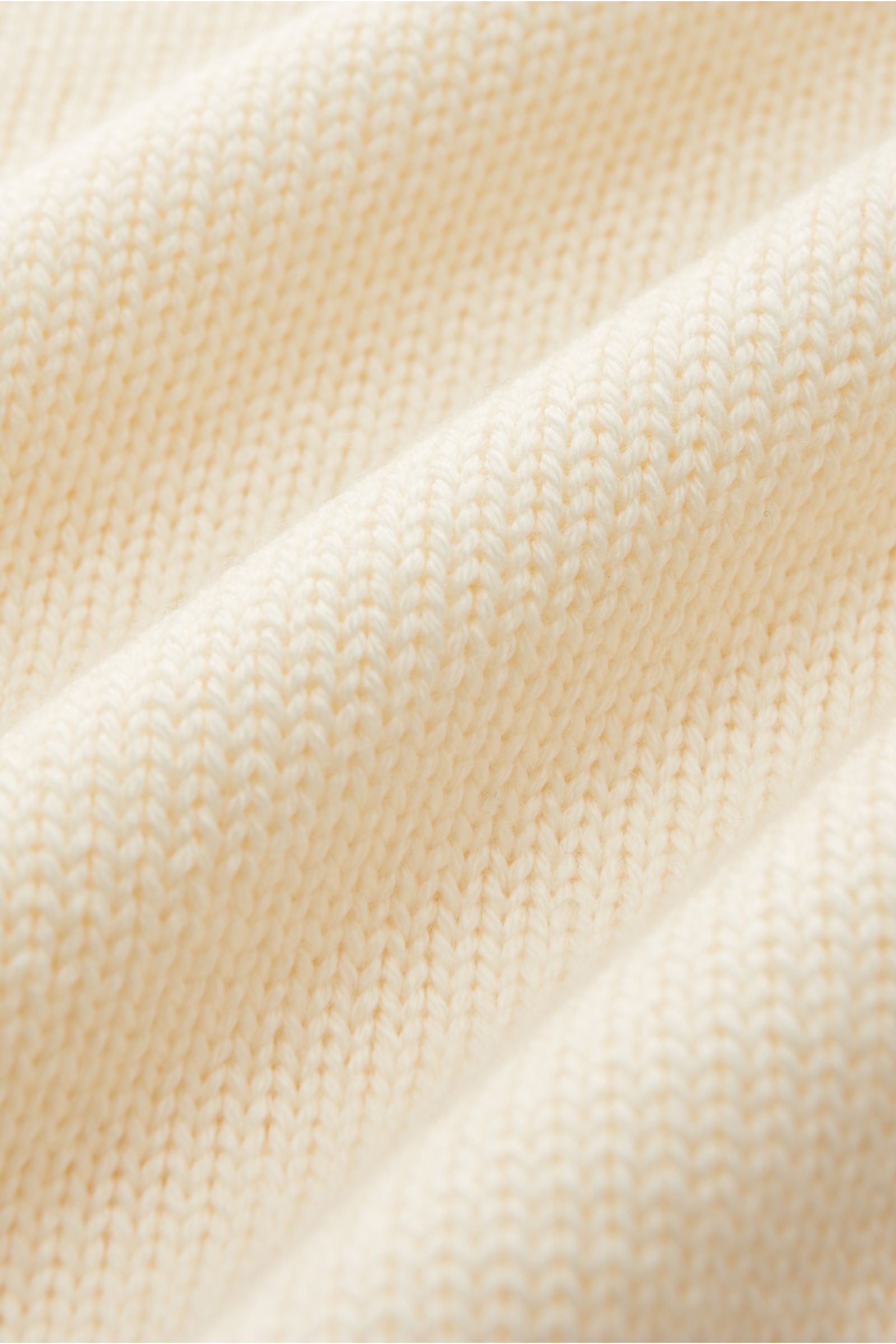 Close-up front perspective of B.F. Knitwear Merino Rollkragenpullover creme showing mittelgrobes Strickbild, reine Merinowolle, weicher Griff, fully fashioned, Slim Fit, gerippter Rollkragen, flexible Rippbündchen.