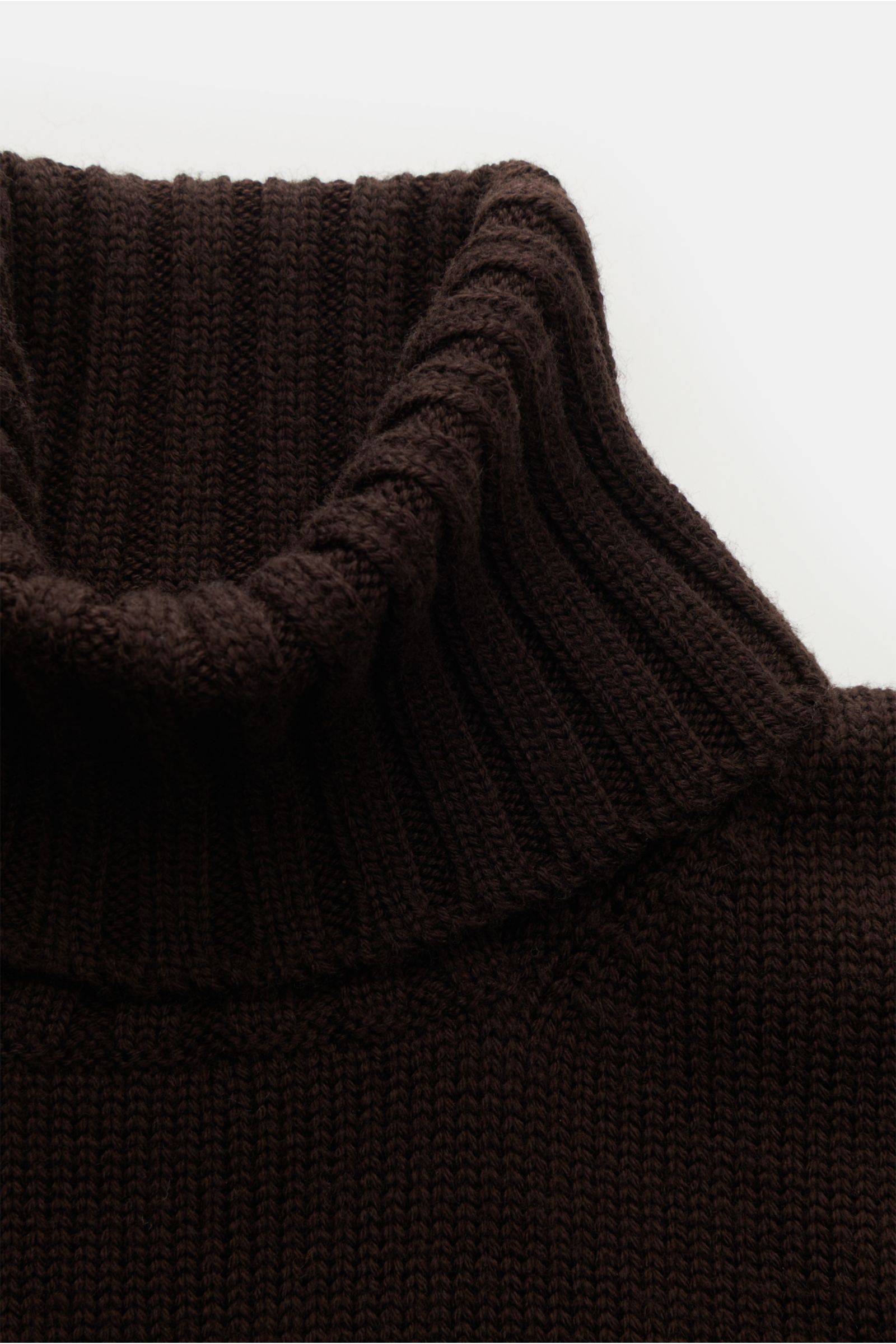 Nahaufnahme des gerippten Rollkragens eines dunkelbraunen B.F. Knitwear Merino Rollkragenpullovers, reine Merinowolle, weicher Griff, fully fashioned, mittelgrobes Strickbild, Slim Fit, flexible Rippbündchen.