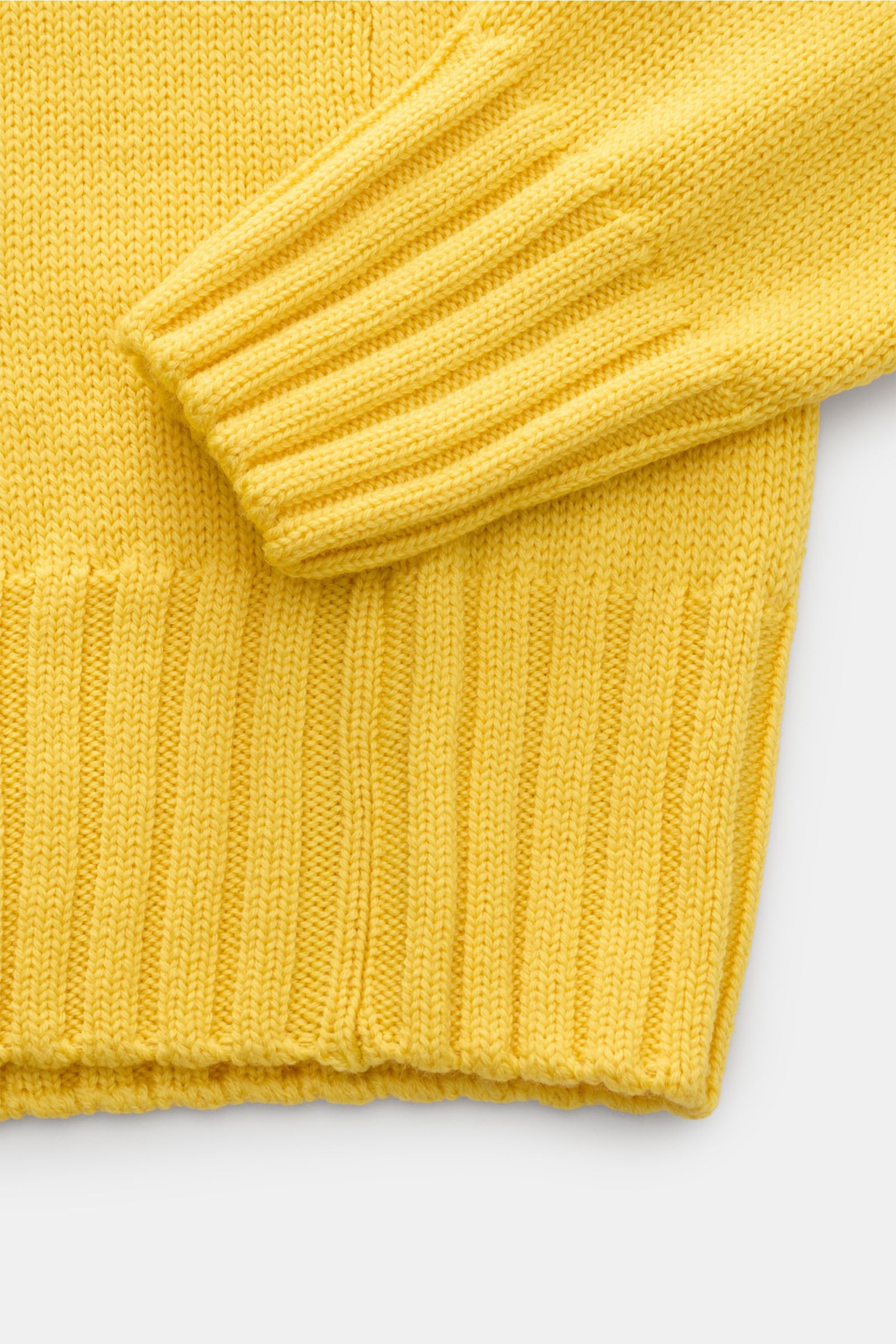 Close-up from above of the sleeve and hem of the B.F. Knitwear Merino turtleneck jumper yellow, showing pure merino wool, soft feel, fully fashioned, semi chunky knit, slim fit, ribbed turtleneck, and flexible ribbed bands.
