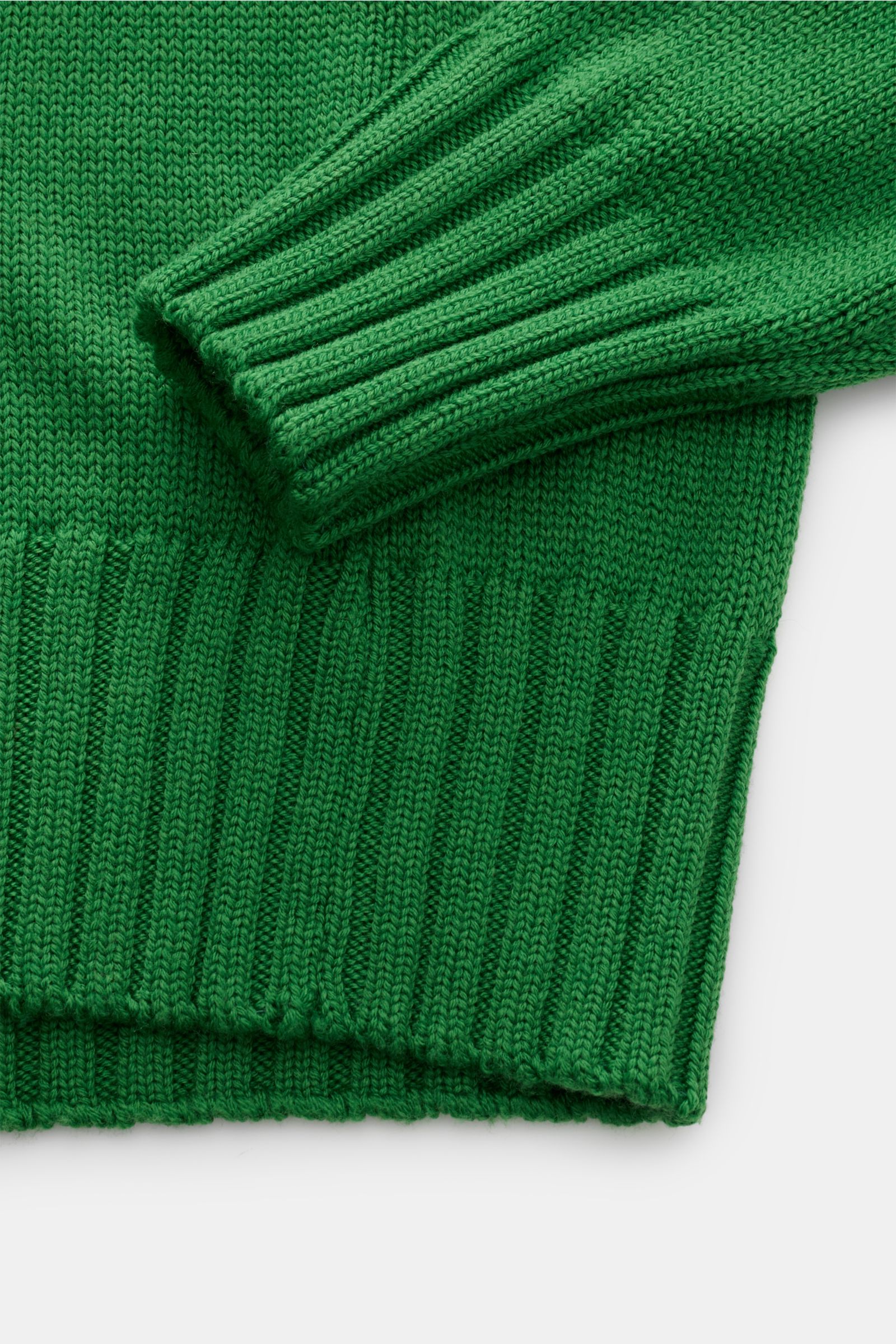 Nahaufnahme von B.F. Knitwear Merino Rollkragenpullover grün aus reiner Merinowolle, weicher Griff, slim fit, mittelgrobes Strickbild, gerippter Rollkragen, flexible Rippbündchen, fully fashioned, von oben fotografiert.