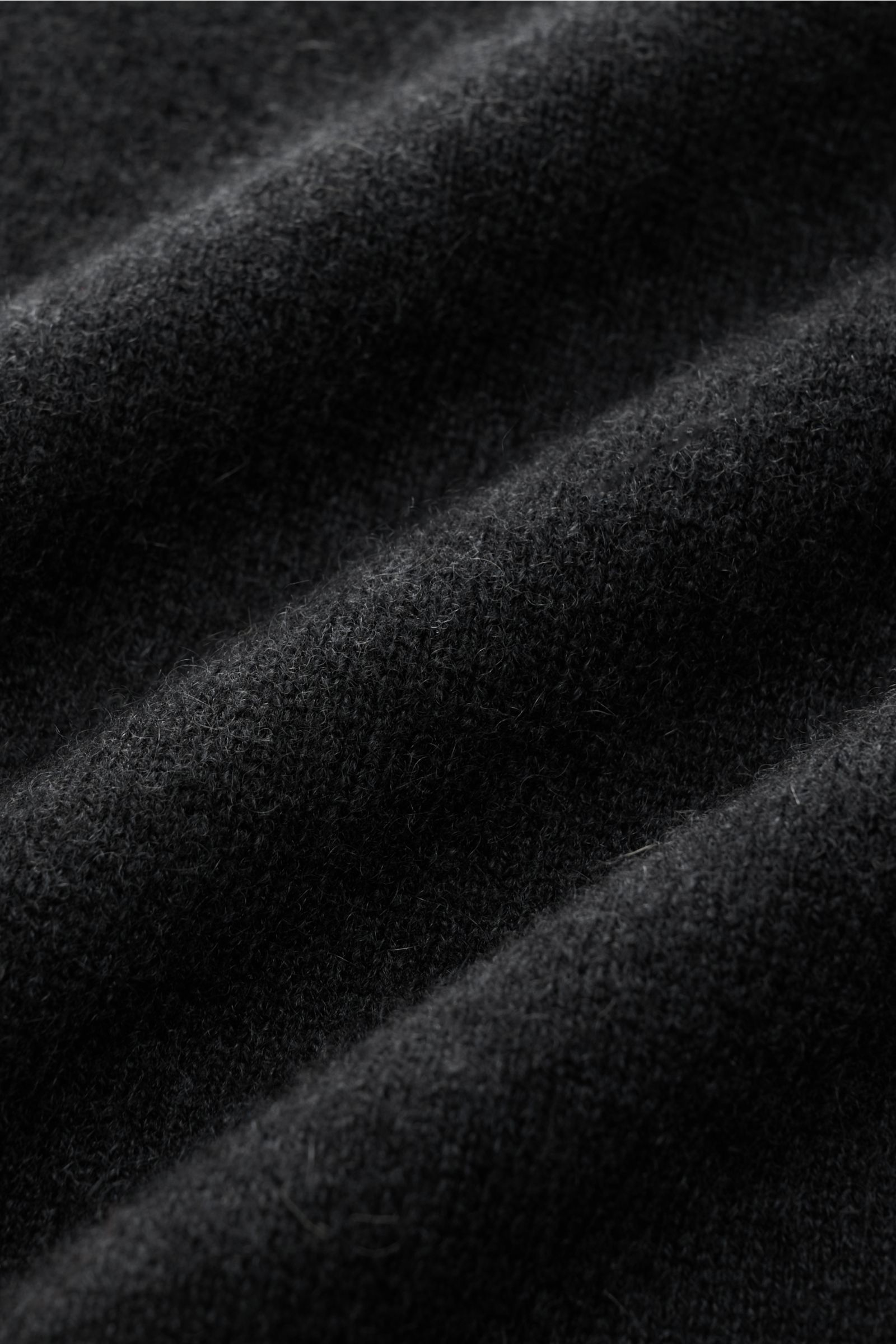 Nahaufnahme des feinen Strickbilds vom FTC Cashmere Rollkragenpullover anthrazit aus reinem Cashmere mit weichem Griff, aufgenommen aus schräger Perspektive.