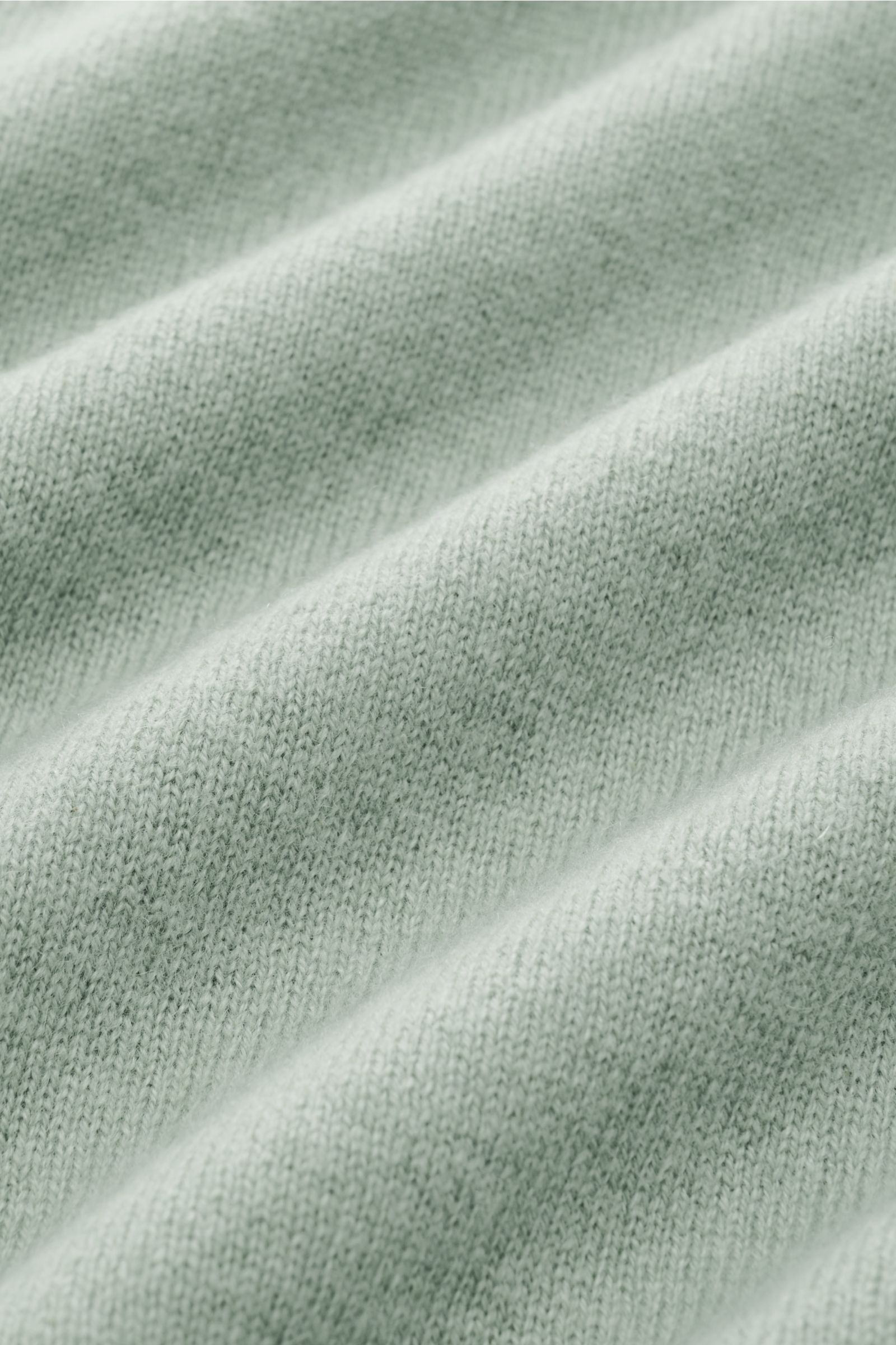 Nahaufnahme des feinen Strickbildes vom FTC Cashmere Rollkragenpullover graugrün meliert aus reinem Cashmere mit weicher Haptik.