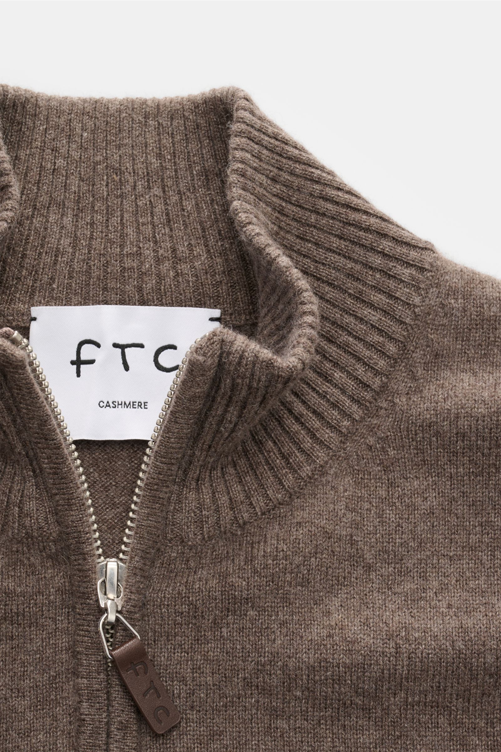 Nahaufnahme des graubraun melierten FTC Cashmere Troyer mit Reißverschluss, Troyer-Kragen, feinem Strickbild und weichem Griff.