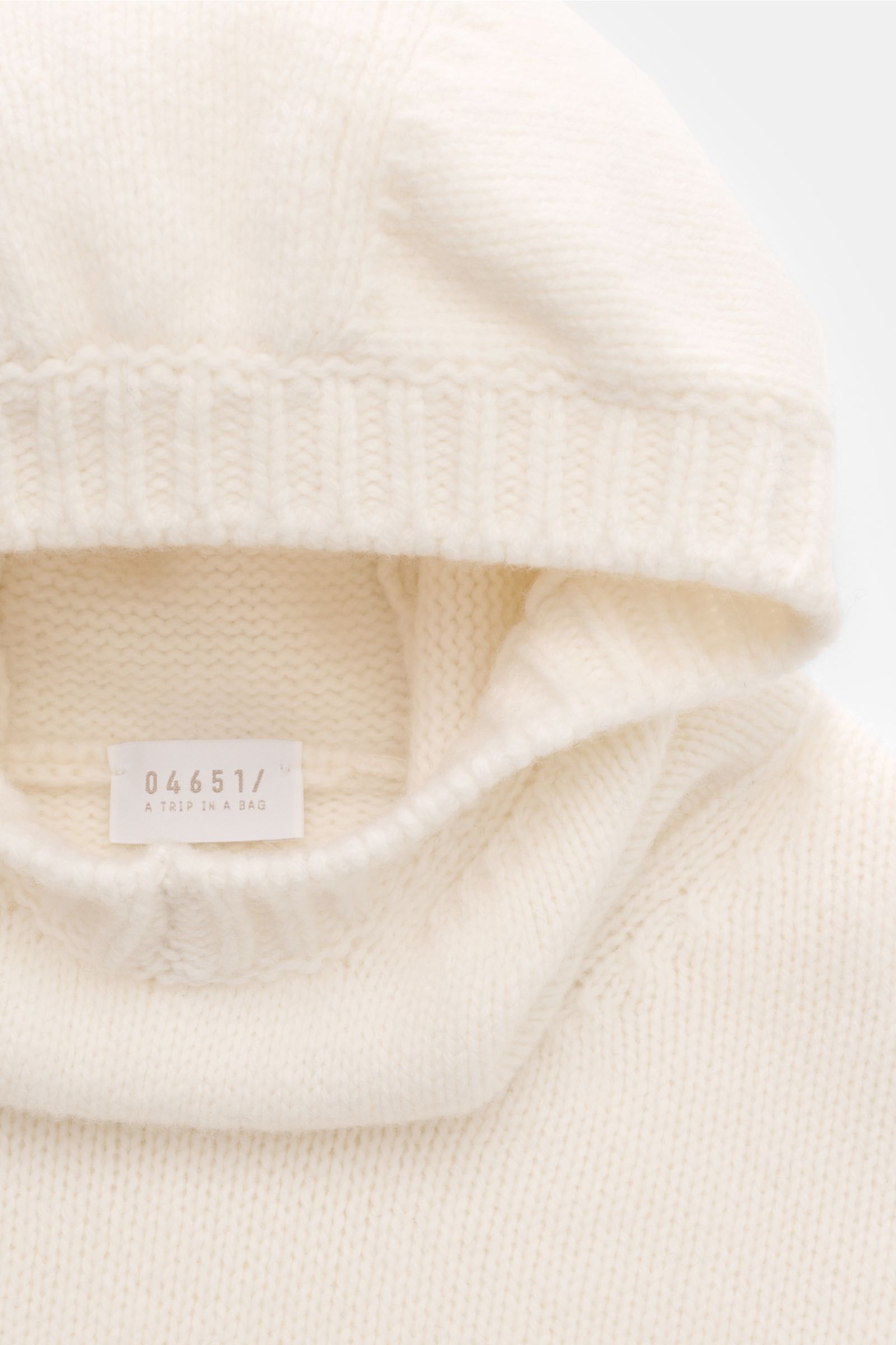 Nahaufnahme von 04651/ A trip in a bag Kapuzenpullover offwhite aus mittelfeinem Strickbild, Regular Fit, Wolle-Cashmere-Mix, weicher Griff, hohem Schalkragen mit Kapuze und breiten Rippbündchen.
