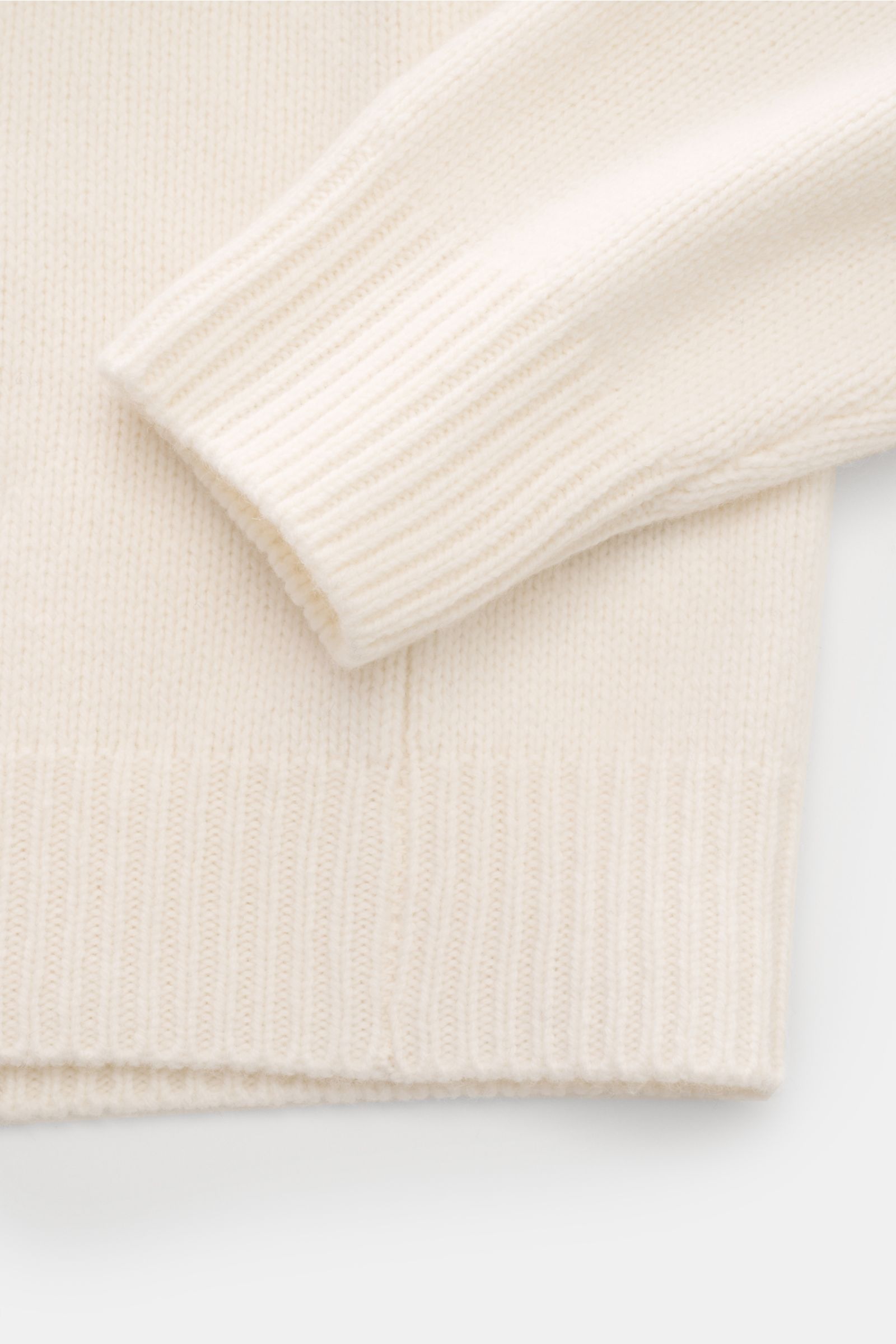 Nahaufnahme des offwhite 04651/ A trip in a bag Kapuzenpullover aus Wolle und Cashmere, weicher Griff, mittelfeines Strickbild, Regular Fit, hoher Schalkragen mit Kapuze, breite Rippbündchen, fotografiert von oben auf Ärmel und Bund.