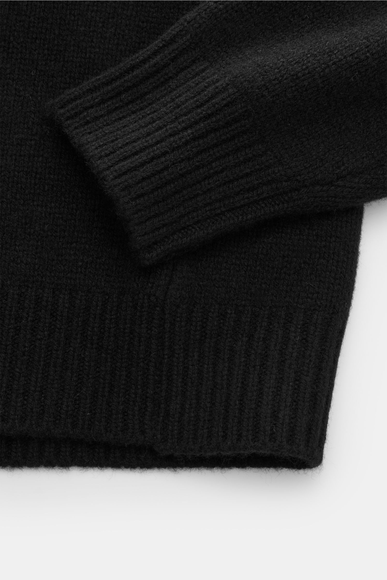 Close-up view of the cuff and hem of the black 04651/ A trip in a bag Kapuzenpullover schwarz, showing a mix of wool and cashmere with a soft touch, medium-fine knit, regular fit, high shawl collar with hood, and wide ribbed cuffs.