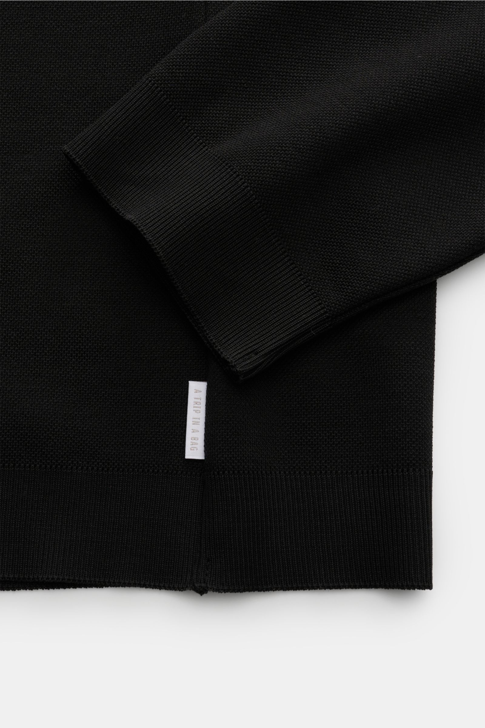 Close-up view of the sleeve and hem of the 04651/ A trip in a bag Rollkragenpullover 'Tp Turtle' schwarz, showing piqué cotton fabric, fine knit, ribbed cuffs, and side seam web label.

Description: Vielseitiges Essential: Mit seinem zeitlosen Design w