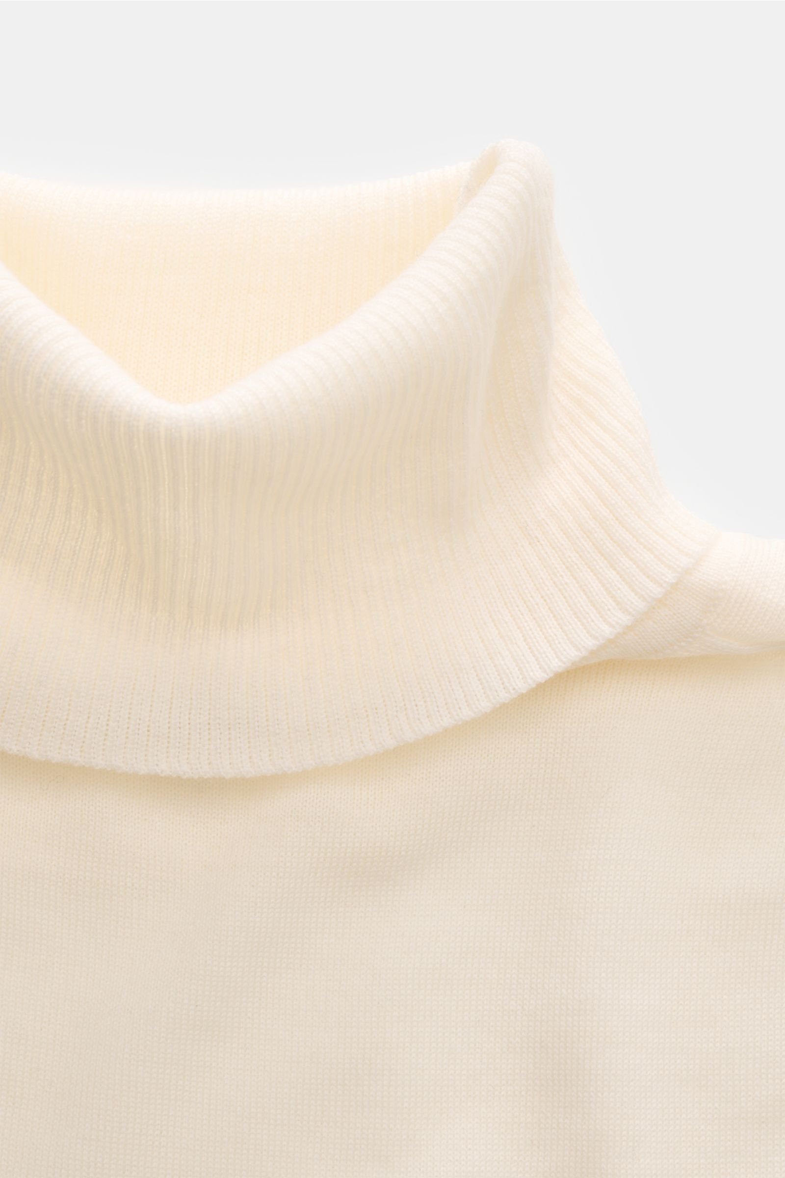 Close-up front view of 04651/ A trip in a bag Merino Rollkragenpullover creme, showing soft, fine-knit cream merino wool with ribbed turtleneck.

Description: Zeitloser Komfort für coole Layerings: Der Rollkragenpullover von 04651/ A TRIP IN A BAG aus 