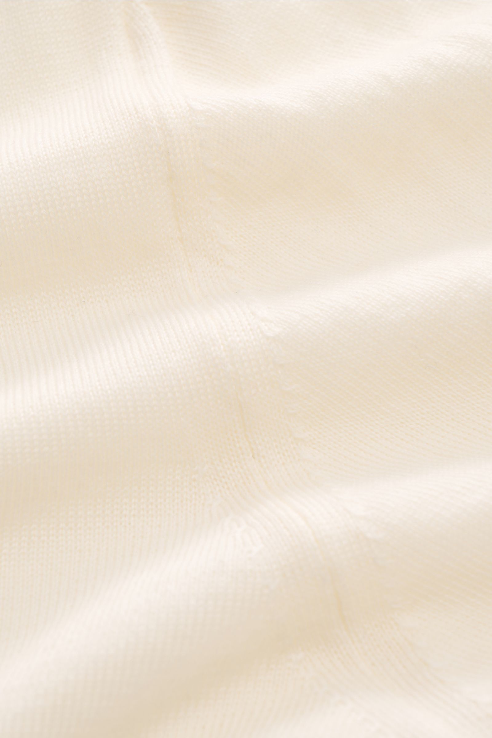 Close-up front view of the 04651/ A trip in a bag Merino Rollkragenpullover creme showing fine knit texture, soft feel, slim fit, ribbed turtleneck, and short hem slits; timeless comfort in pure merino wool for layering and everyday wear. Zeitloser Kom