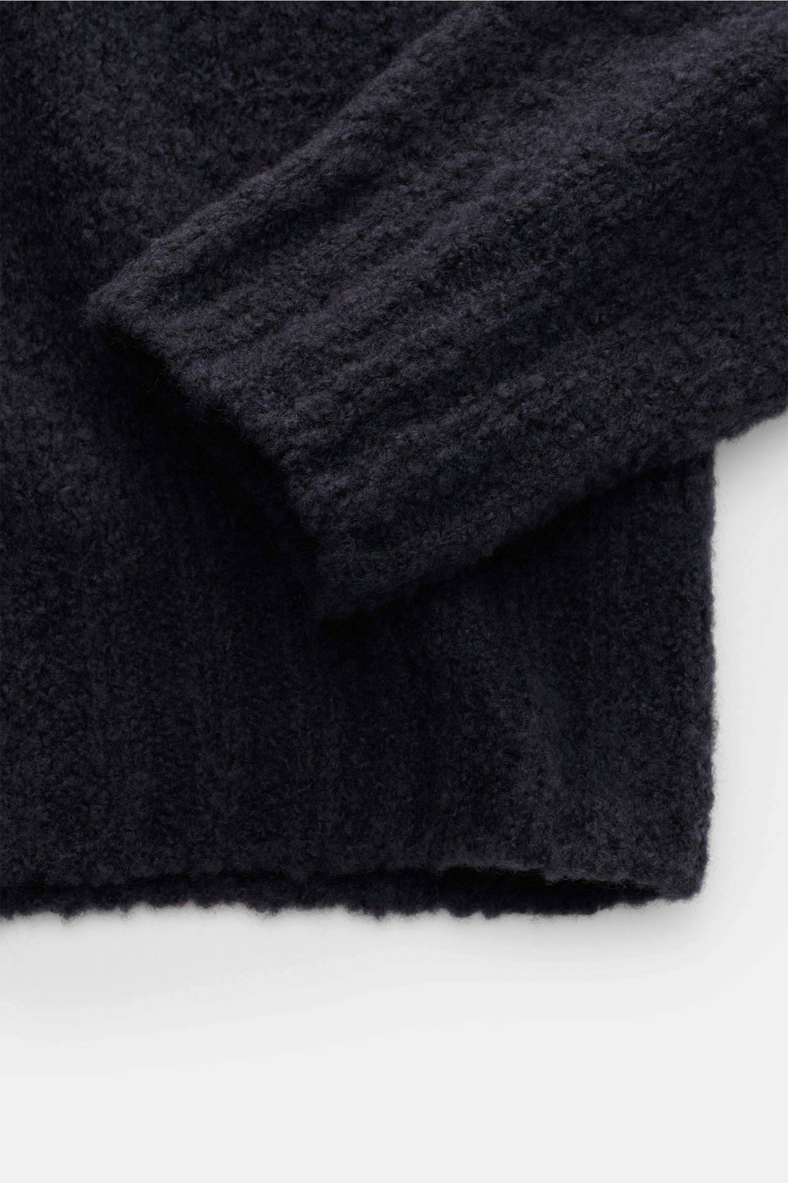 Close-up from above of the sleeve and hem of the 04651/ A trip in a bag Rollkragenpullover 'Chunky Turtle' navy, showing its voluminous knit texture and soft ribbed cuffs. 

Edles Winter-Essential: Der legere 'Chunky Turtle' Rollkragenpullover von 0465