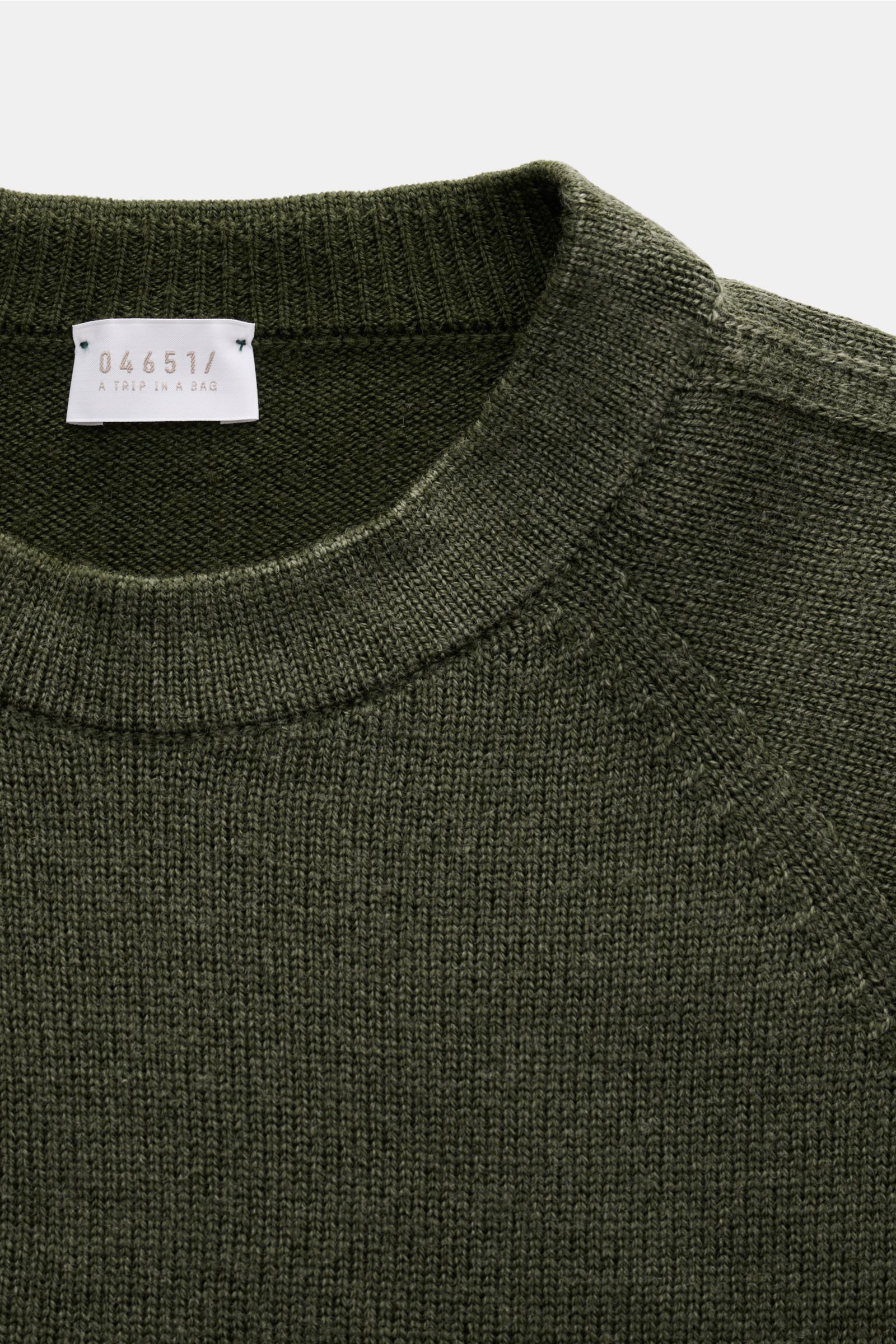 Close-up front view of the dark green 04651/ A trip in a bag reversible crew neck jumper 'Foggy Crew' showing knit texture and ribbed collar.

Description: This reversible jumper 'Foggy Crew' made of pure virgin wool by 04651/ A TRIP IN A BAG gets its 