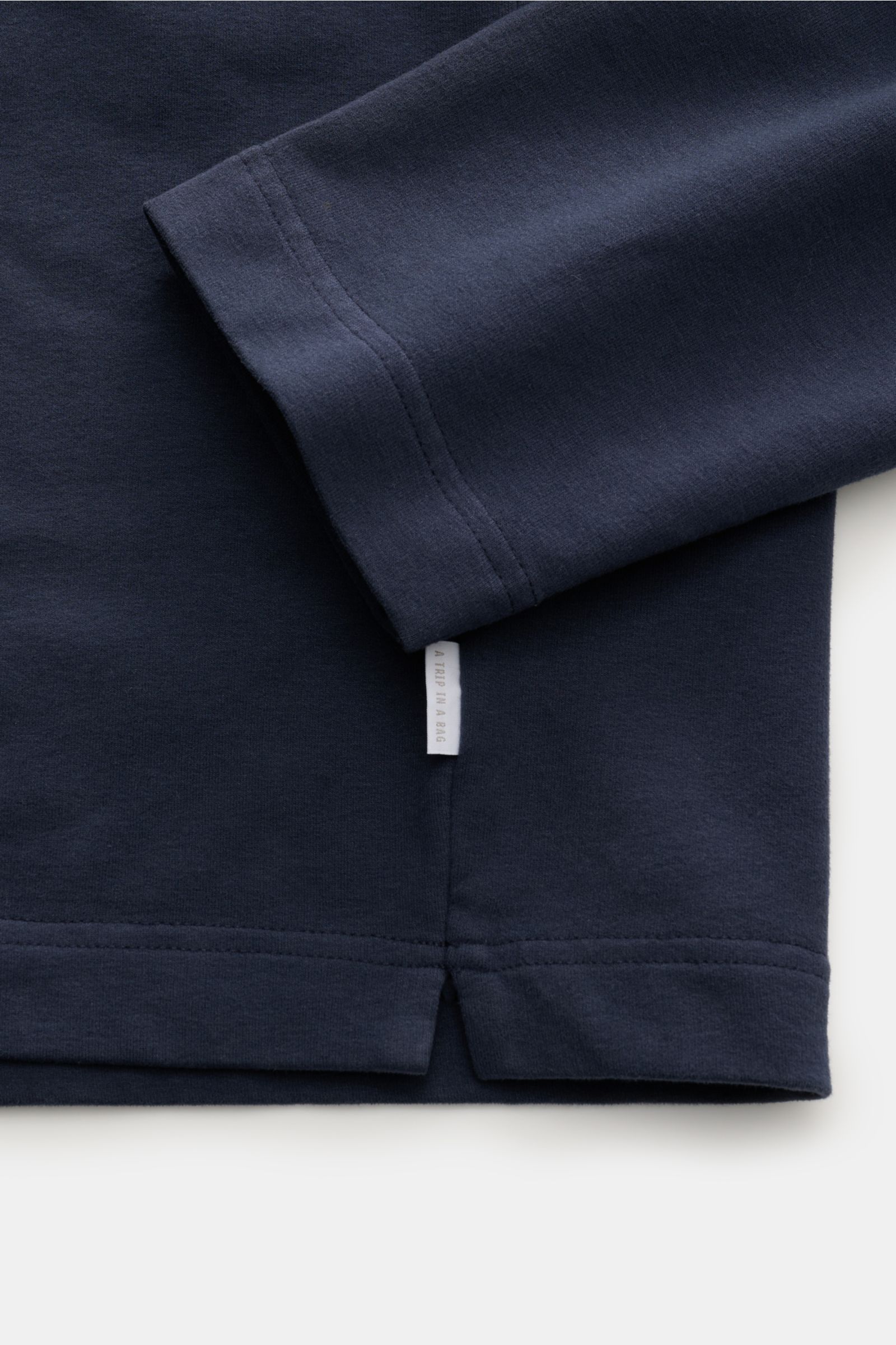 Nahaufnahme des navyfarbenen 04651/ A trip in a bag Rollkragenpullover 'If Turtle' mit weichem Baumwoll-Microfaser-Stoff, Regular Fit, anliegendem Rollkragen und Weblabel in der Seitennaht, fotografiert von unten seitlich.