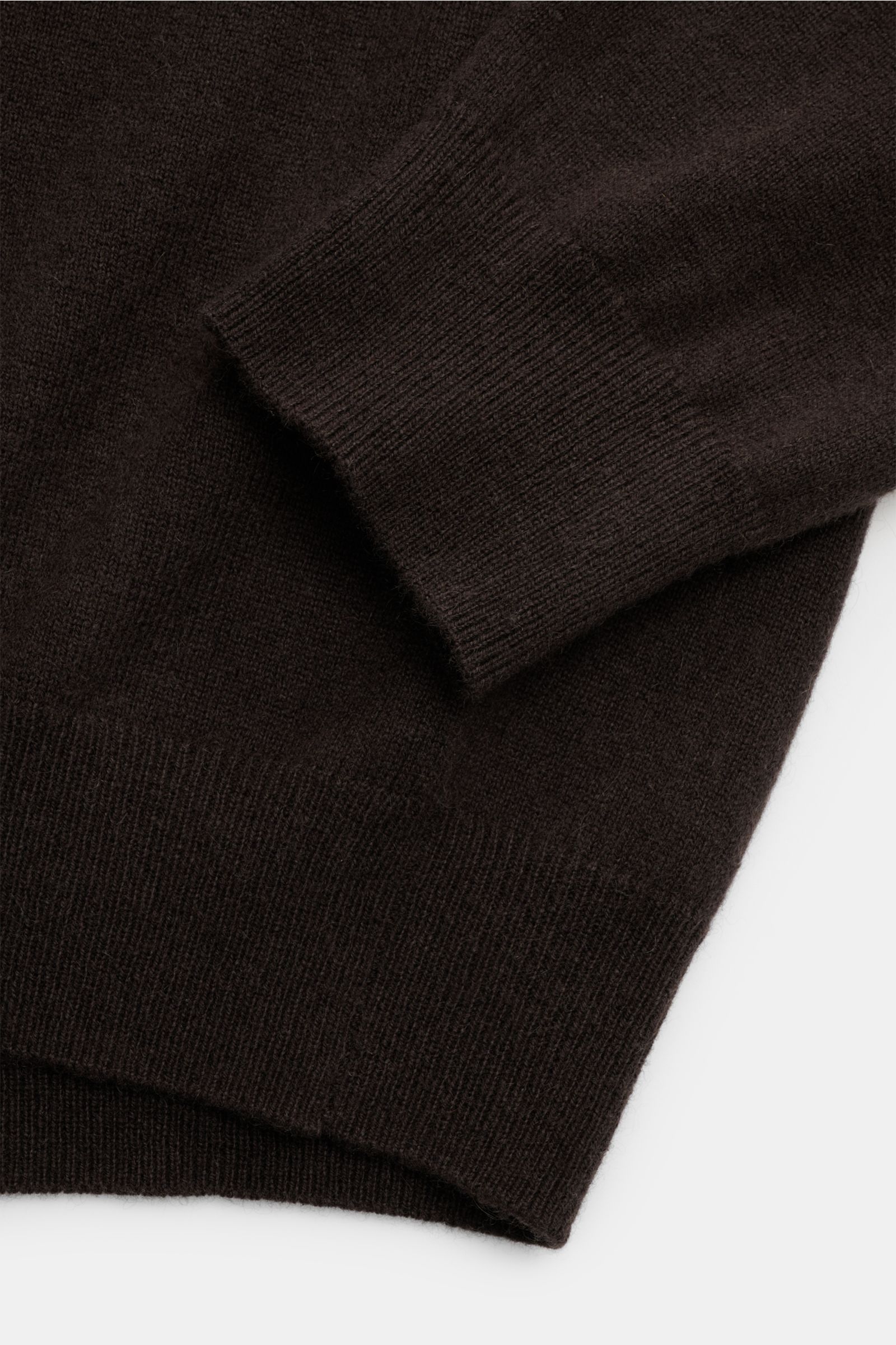 Nahaufnahme von Ärmel und Bund des von Braun Cashmere Rollkragenpullovers dunkelbraun, slim fit, feines Strickbild, weicher Griff, elastische Rippbündchen.