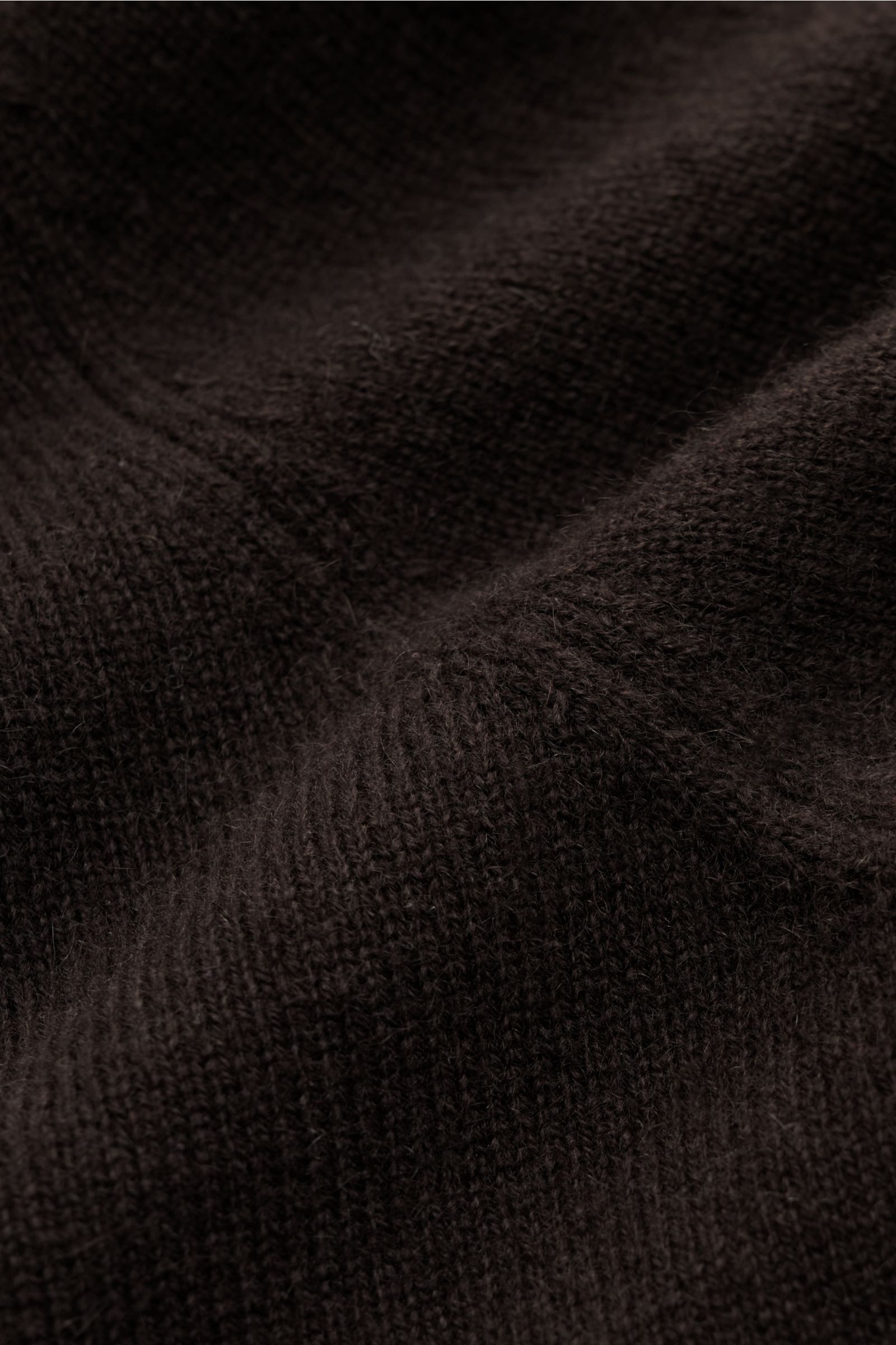 Nahaufnahme des fein gestrickten, dunkelbraunen von Braun Cashmere Rollkragenpullovers mit weichem Griff und elastischen Rippbündchen.