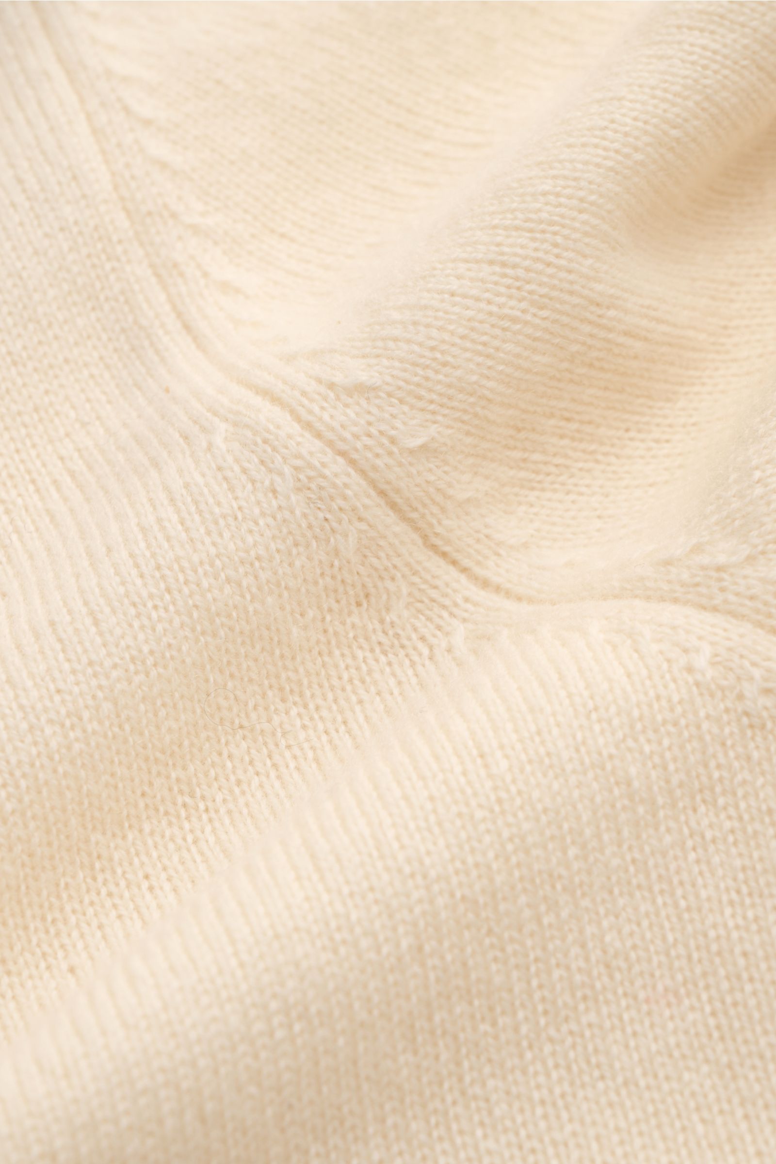 Nahaufnahme des fein gestrickten, cremefarbenen von Braun Cashmere Rollkragenpullovers mit weichem Griff, Slim Fit und elastischen Rippbündchen.