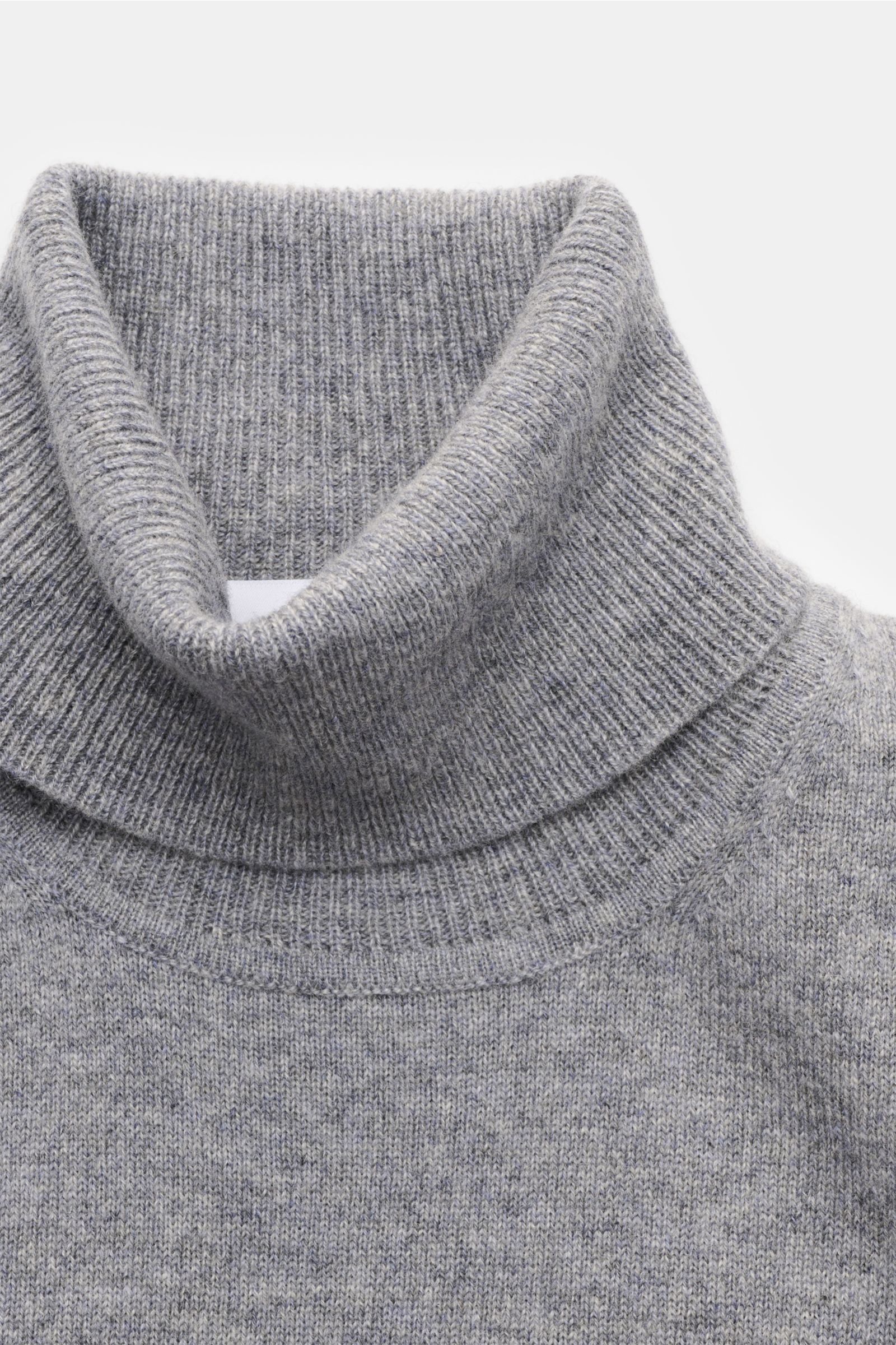 Nahaufnahme von einem von Braun Cashmere Rollkragenpullover grau meliert, fein gestrickt aus reinem Cashmere mit weichem Griff, Slim Fit, anliegendem Rollkragen und elastischen Rippbündchen, aus der Mongolei, frontal fotografiert.