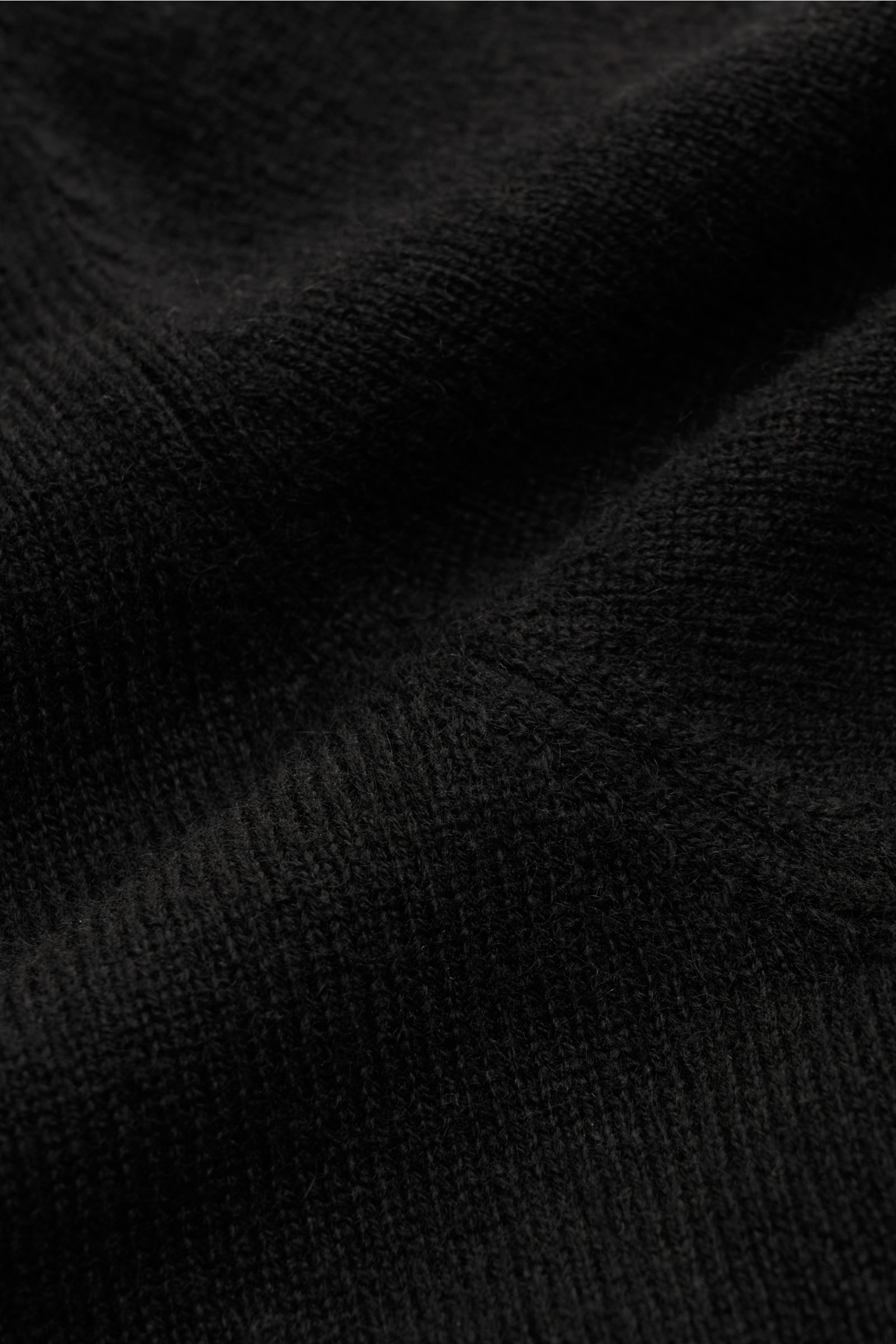 Nahaufnahme des feinen Strickbilds und der weichen Struktur des von Braun Cashmere Rollkragenpullovers schwarz aus reinem Cashmere.