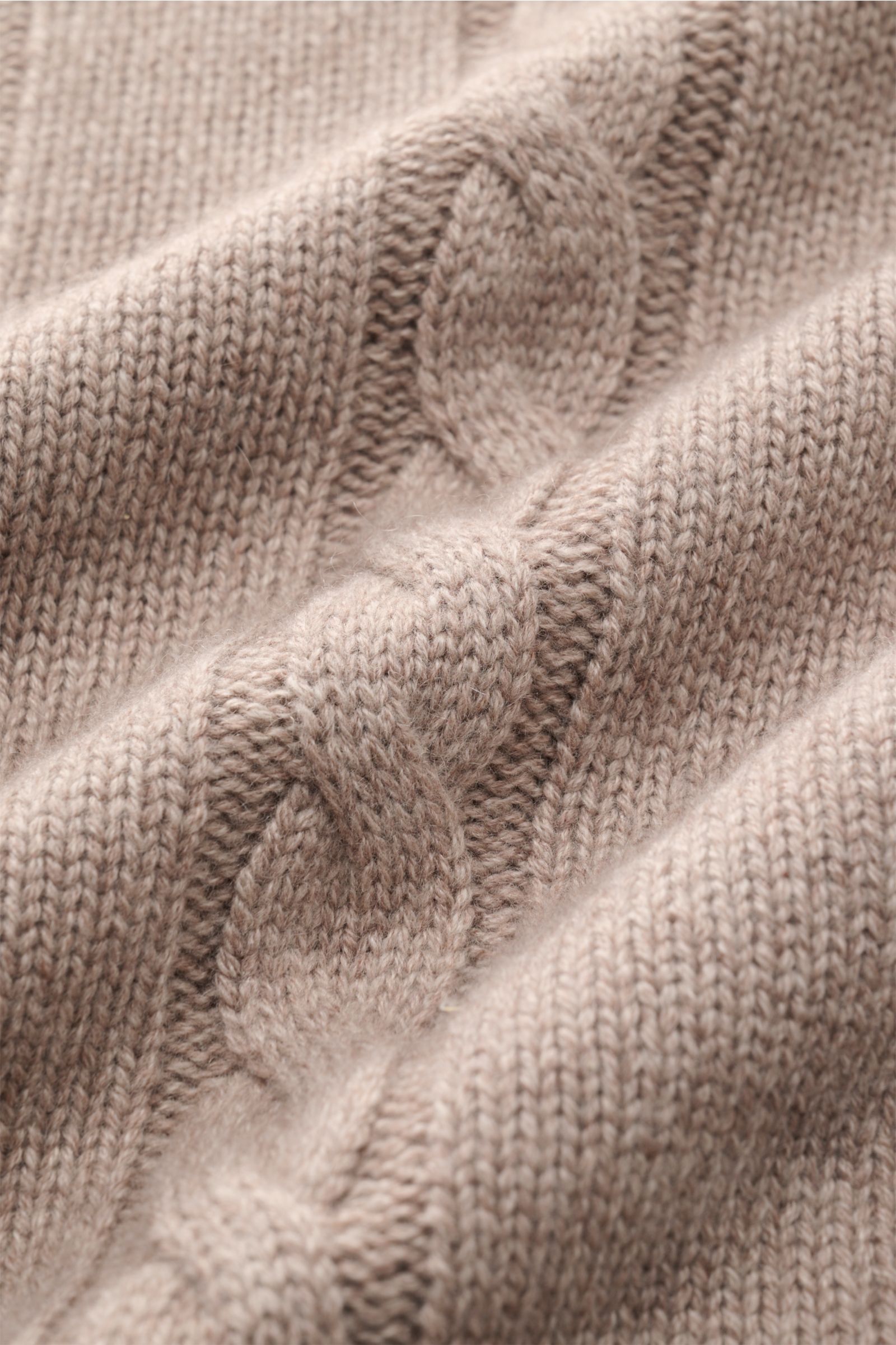 Nahaufnahme des von Braun Cashmere Rollkragenpullovers beige, fotografiert von oben, zeigt feinen, weichen reinen Cashmere mit Linksstrick- und Zopfstrickmuster.