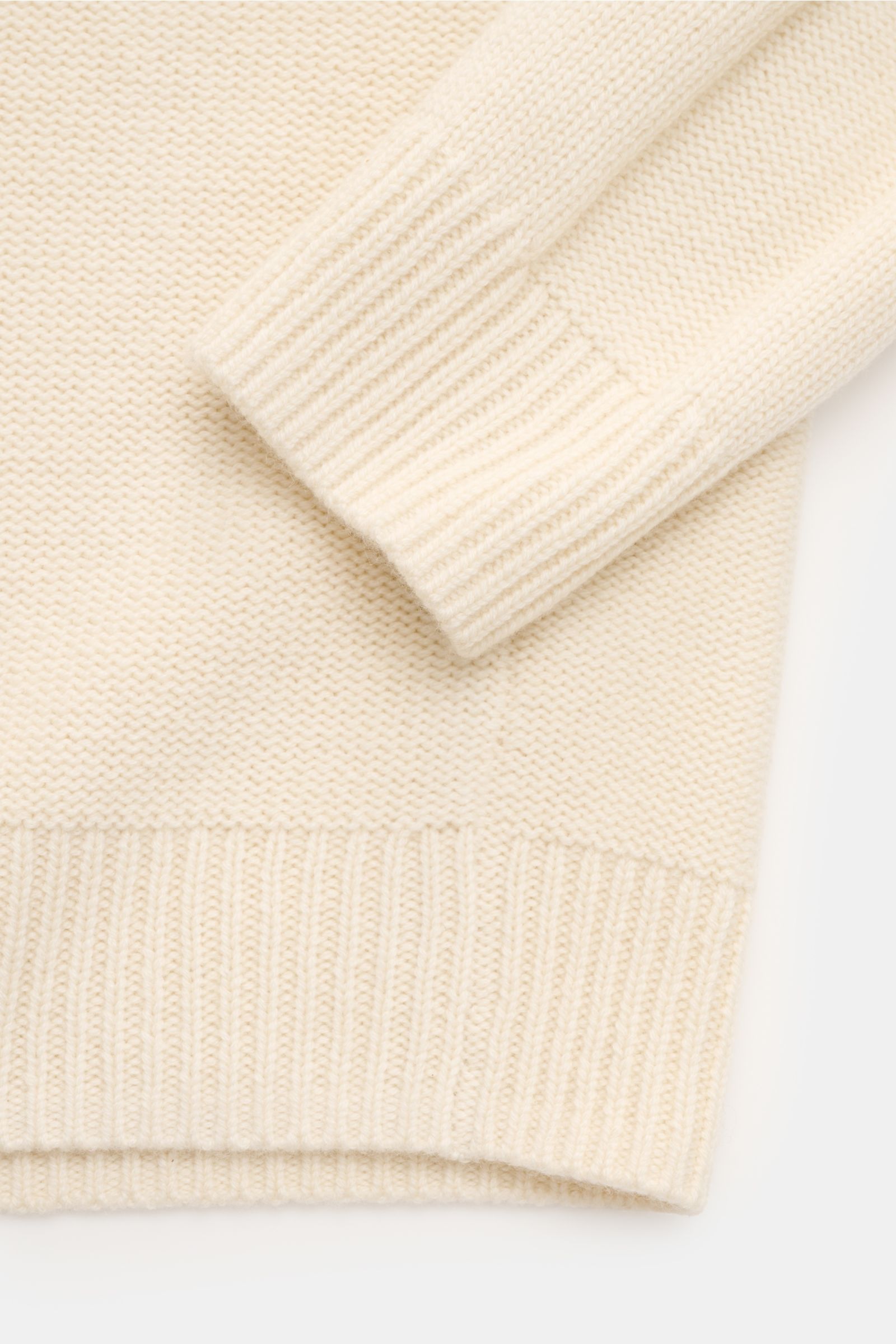 Nahaufnahme des von Braun Cashmere Rollkragenpullovers offwhite von oben, zeigt weichen, mittelfeinen Strick mit Links- und Zopfmuster, Slim Fit, anliegendem Rollkragen und flexiblen Rippbündchen aus reinem Cashmere.