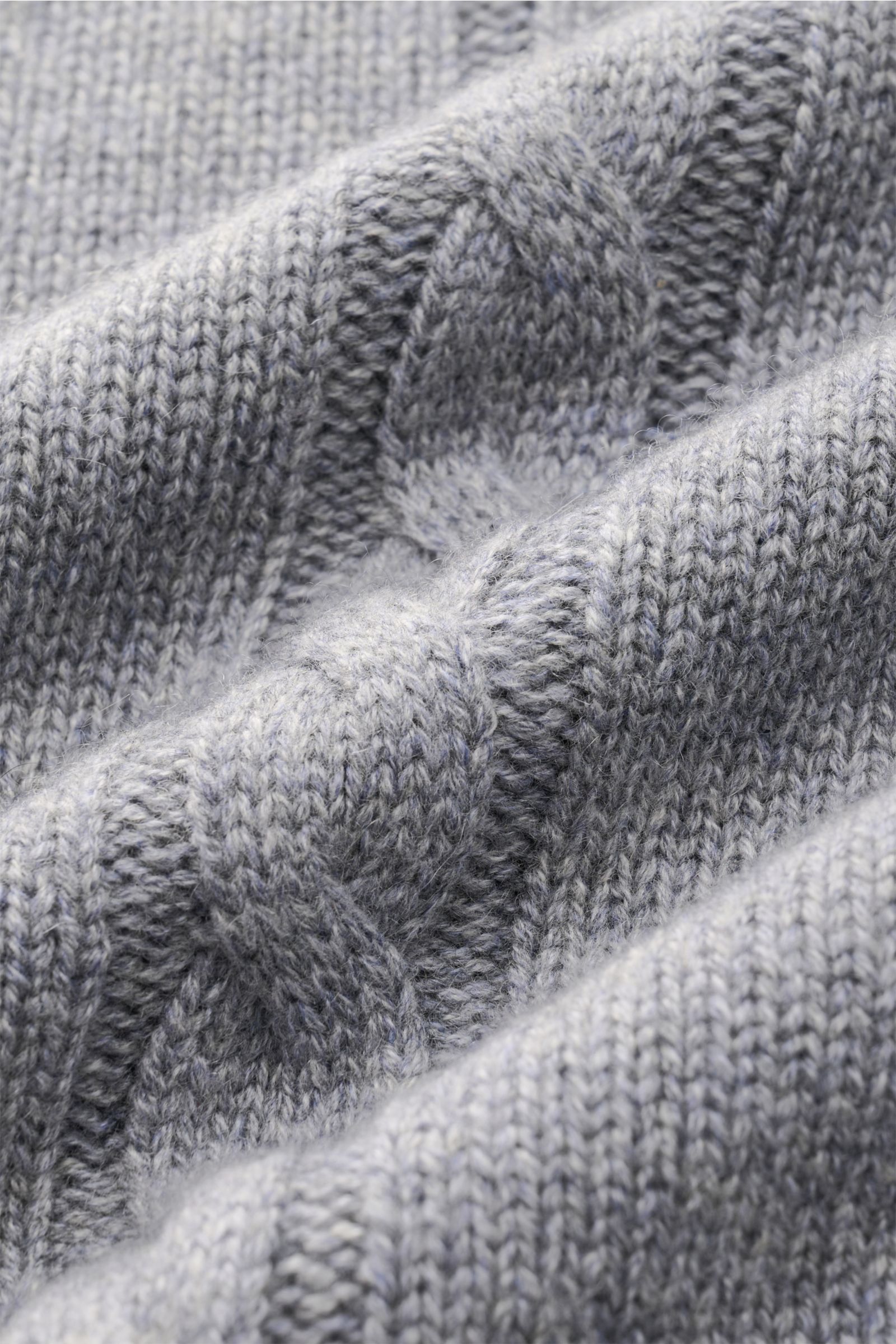 Nahaufnahme des von Braun Cashmere Rollkragenpullovers grau, fotografiert aus schräger Perspektive, zeigt weichen Links- und Zopfstrick.