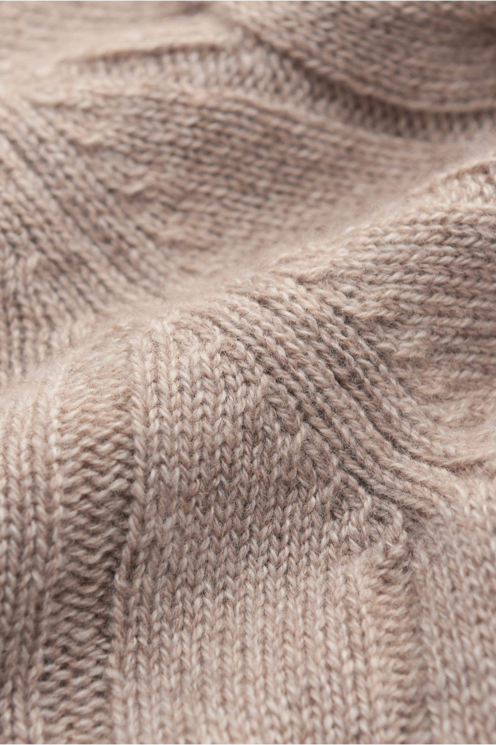 Nahaufnahme eines beige melierten von Braun Cashmere Rollkragenpullovers mit zeitlosem Zopfstrickmuster, weichem Griff und flexiblem Rippbündchen.