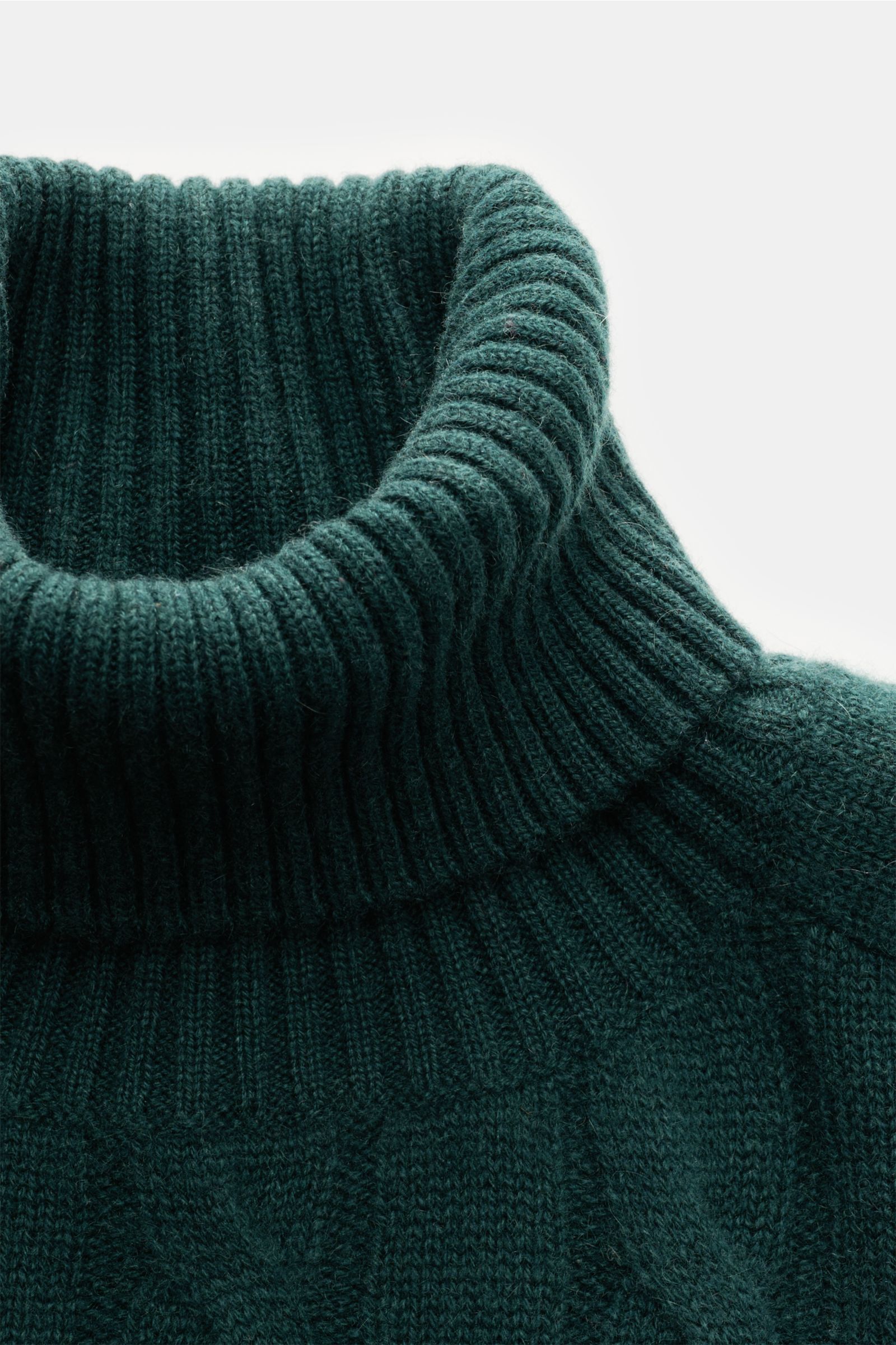 Nahaufnahme von dunkelgrünem von Braun Cashmere Rollkragenpullover mit zeitlosem Zopfstrickmuster, weichem Griff, Regular Fit, anliegendem Rollkragen und flexiblen Rippbündchen. Komfortabel durch die Winterzeit dank reinem Cashmere aus der inneren Mongole