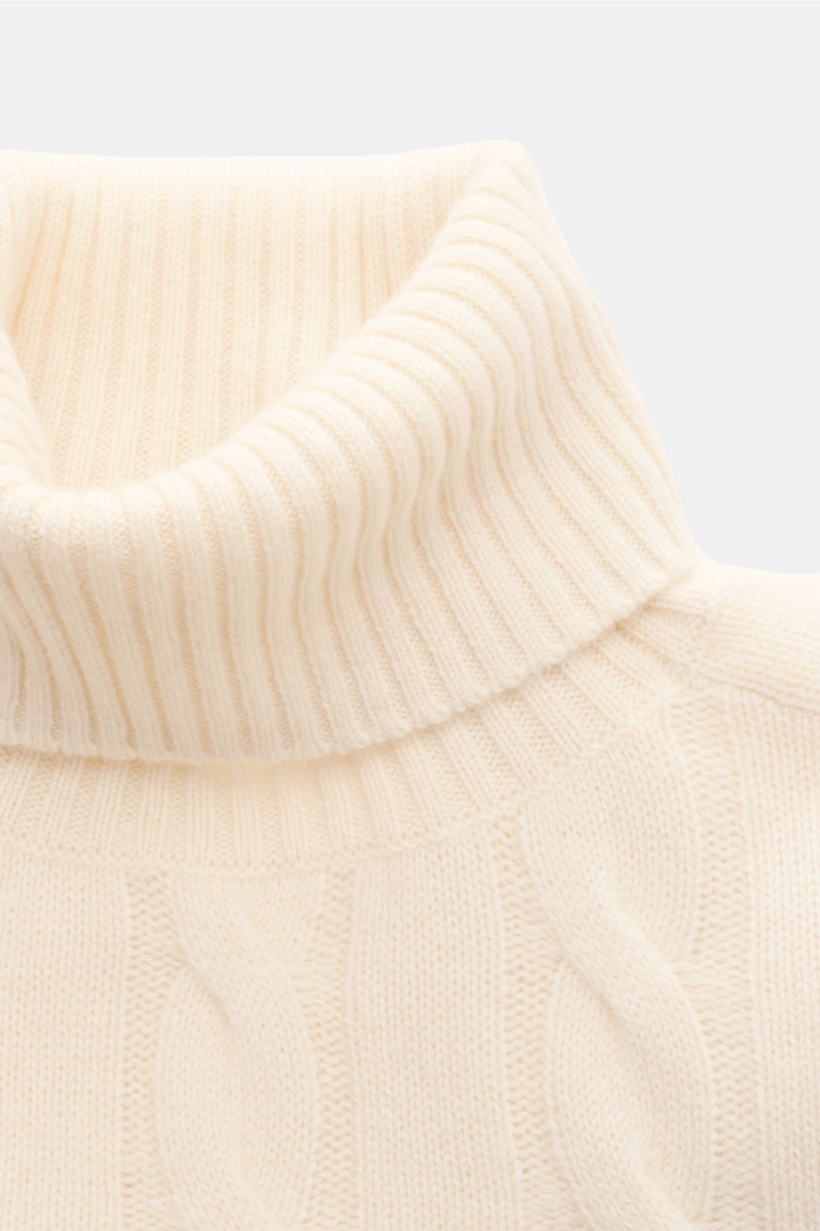 Nahaufnahme des von Braun Cashmere Rollkragenpullovers creme, aus softer, reiner Mongolei-Cashmere mit zeitlosem Zopfstrickmuster, Regular Fit, anliegendem Rollkragen und flexiblen Rippbündchen, fotografiert von vorne.