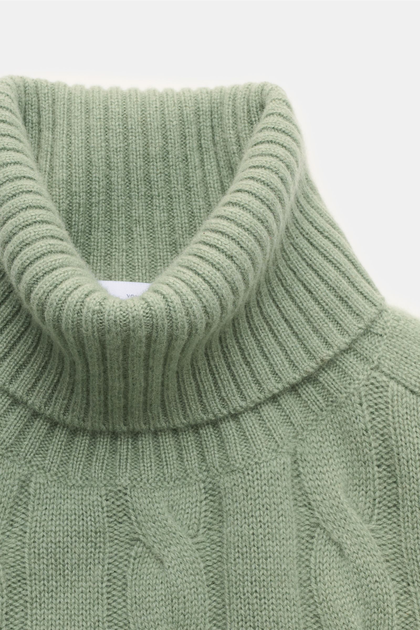 Nahaufnahme des von Braun Cashmere Rollkragenpullovers graugrün aus reiner, softer Mongolei-Cashmere mit zeitlosem Zopfstrickmuster, Regular Fit, anliegendem Rollkragen und flexiblen Rippbündchen, fotografiert von oben.