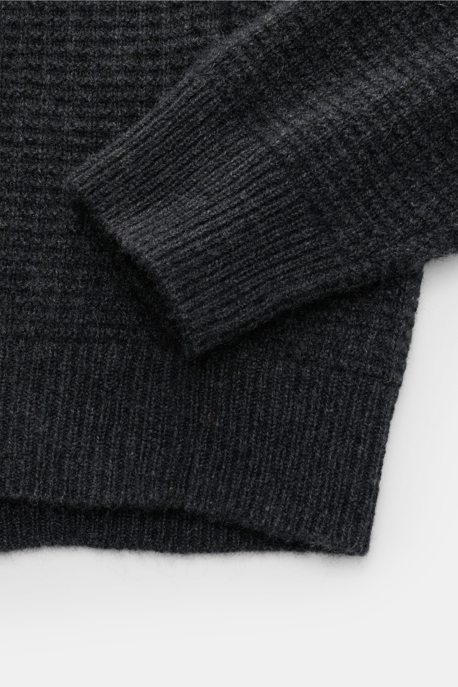 Close-up photo of the sleeve and hem from above of the von Braun Cashmere mock neck jumper anthracite mottled in fine textured knit. Get ready for the colder months with VON BRAUN: This jumper with mock neck in pure, Mongolian cashmere in an elegant te