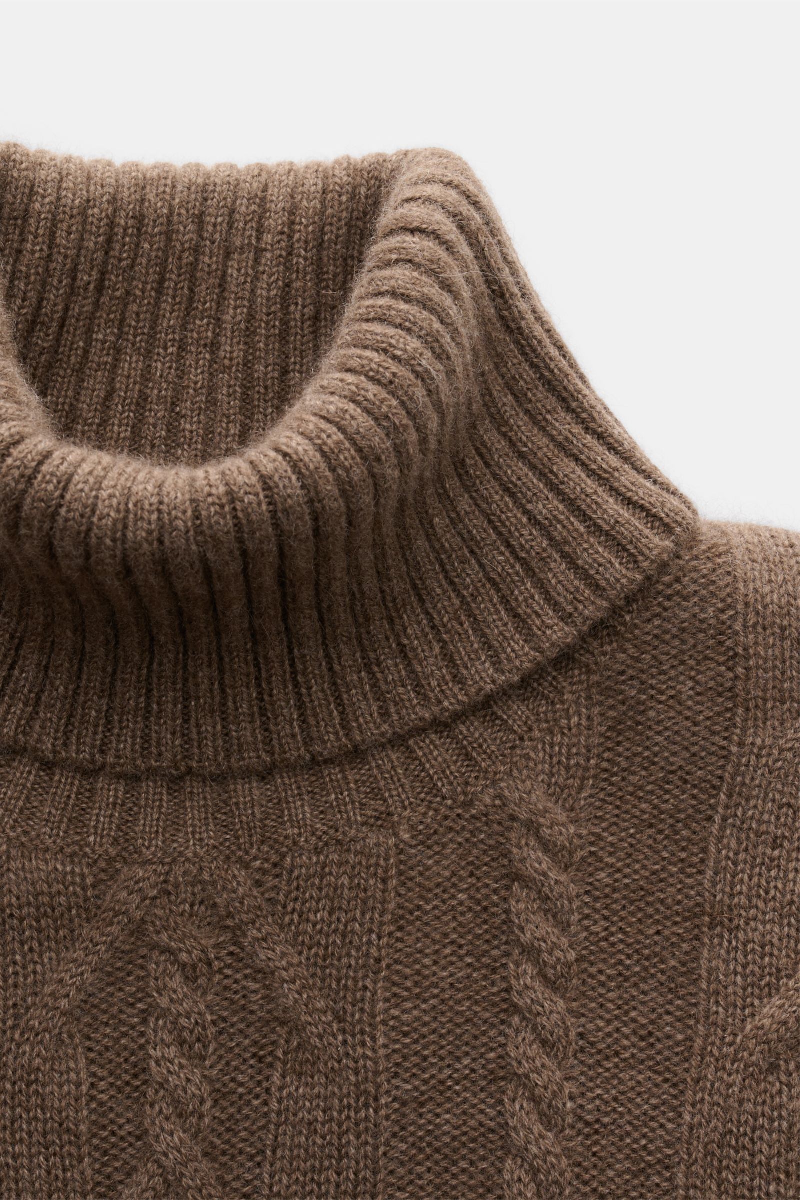 Nahaufnahme von braun meliertem von Braun Cashmere Rollkragenpullover, seitlich oben fotografiert, mit Zopfstrickmuster und flexiblem Rippbündchen.