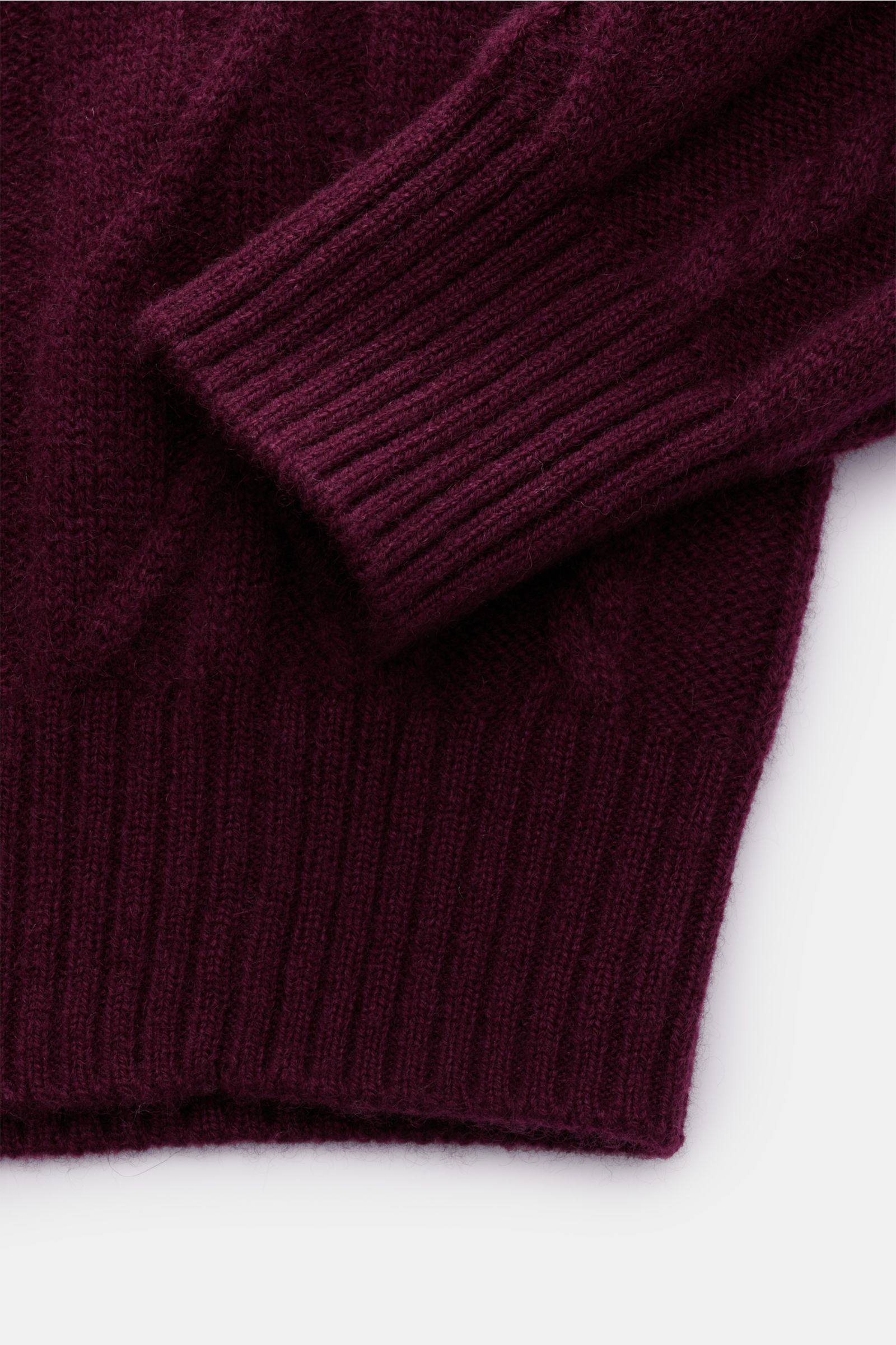 Nahaufnahme eines von Braun Cashmere Rollkragenpullovers bordeaux, fotografiert von oben, mit weichem Zopfstrick und flexiblen Rippbündchen.