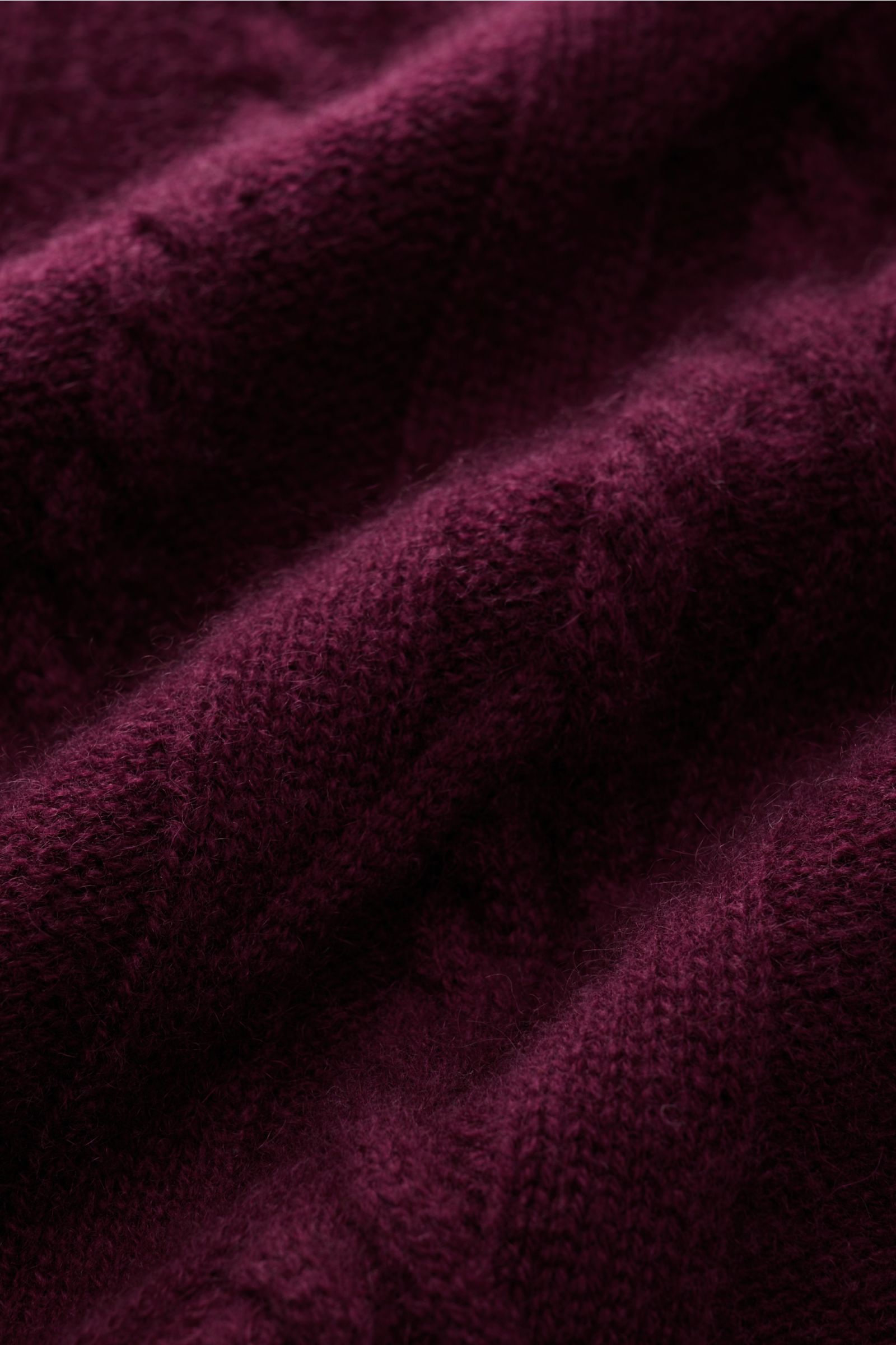 Nahaufnahme des von Braun Cashmere Rollkragenpullovers bordeaux mit zeitlosem Zopfstrickmuster und weichem, mittelfeinem Strickbild.