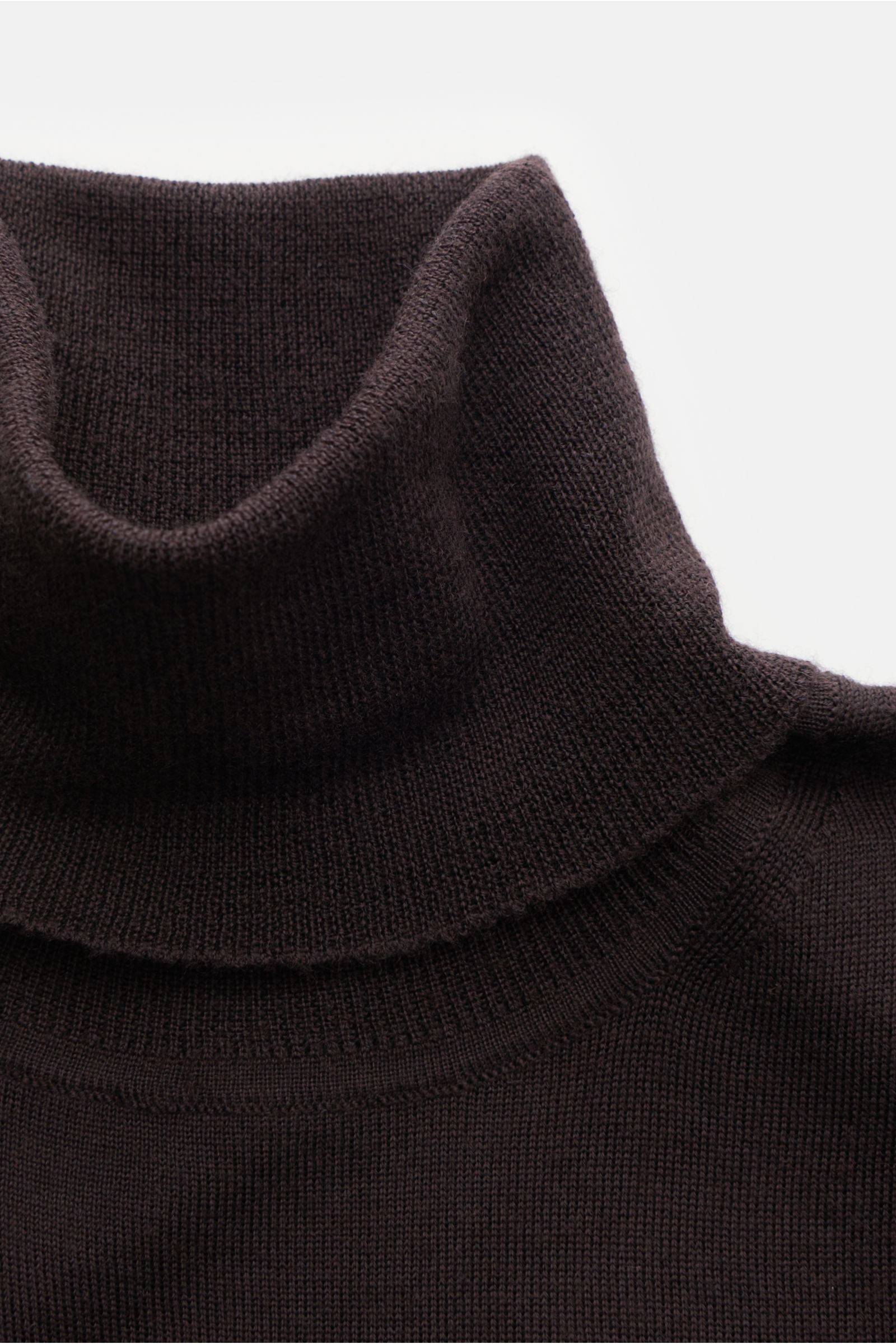 Nahaufnahme des von Braun Merino Rollkragenpullovers dunkelbraun, superfein gestrickt, Slim Fit mit anliegendem Rollkragen und flexiblen Rippbündchen aus reiner Merinowolle.