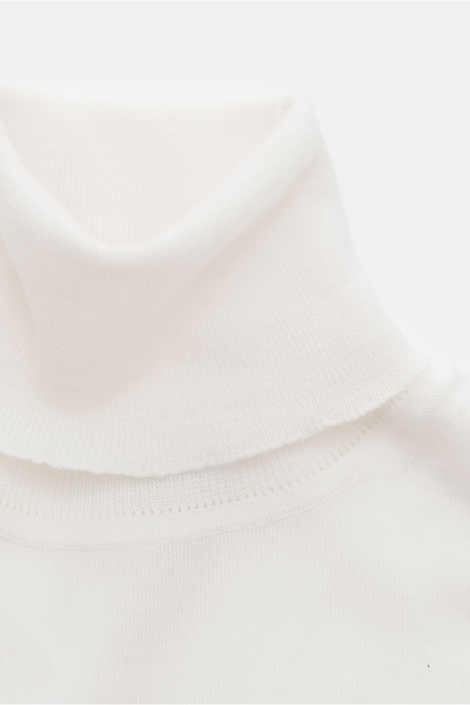Nahaufnahme von einem cremefarbenen von Braun Merino Rollkragenpullover, superfein gestrickt aus reiner Merinowolle, Slim Fit mit anliegendem Rollkragen und flexiblen Rippbündchen, fotografiert von oben.