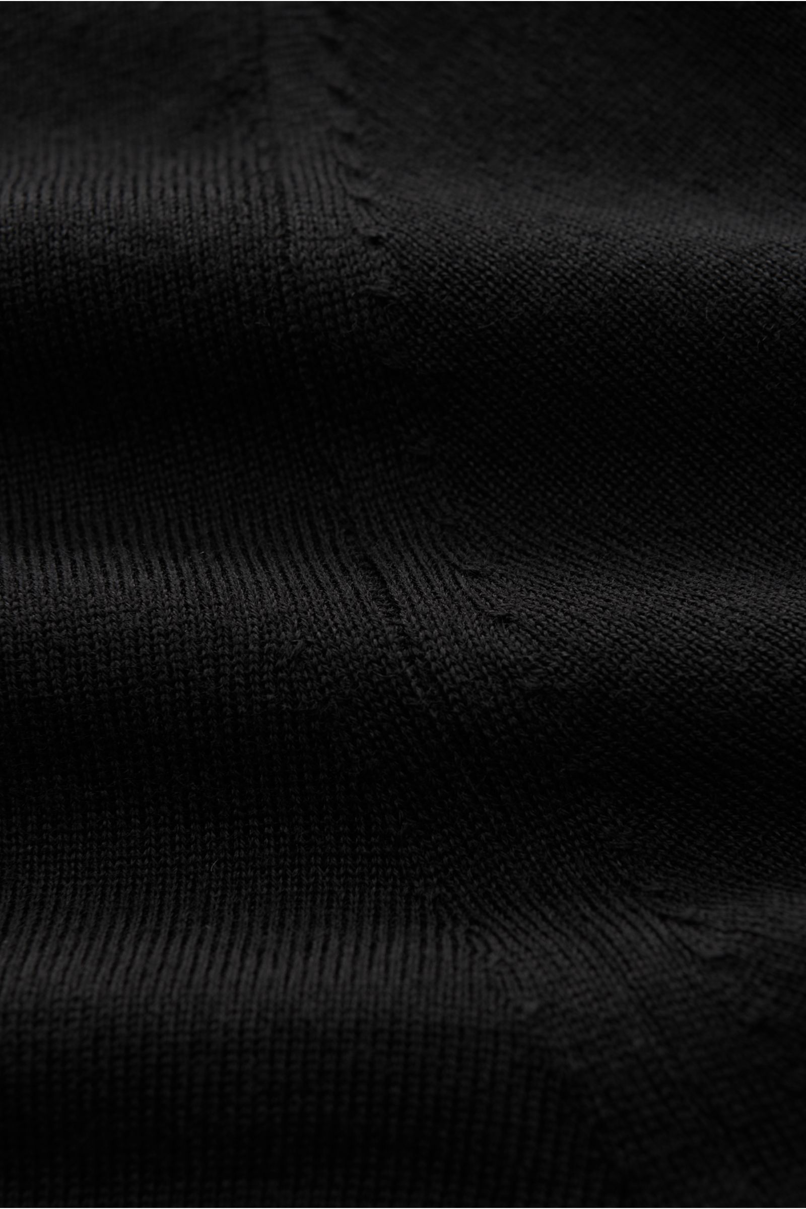 Nahaufnahme des schwarzen von Braun Merino Rollkragenpullovers, superfein gestrickt aus reiner Merinowolle, Slim Fit mit anliegendem Rollkragen und flexiblen Rippbündchen, Detail der feinen Strickstruktur aus seitlicher Perspektive.