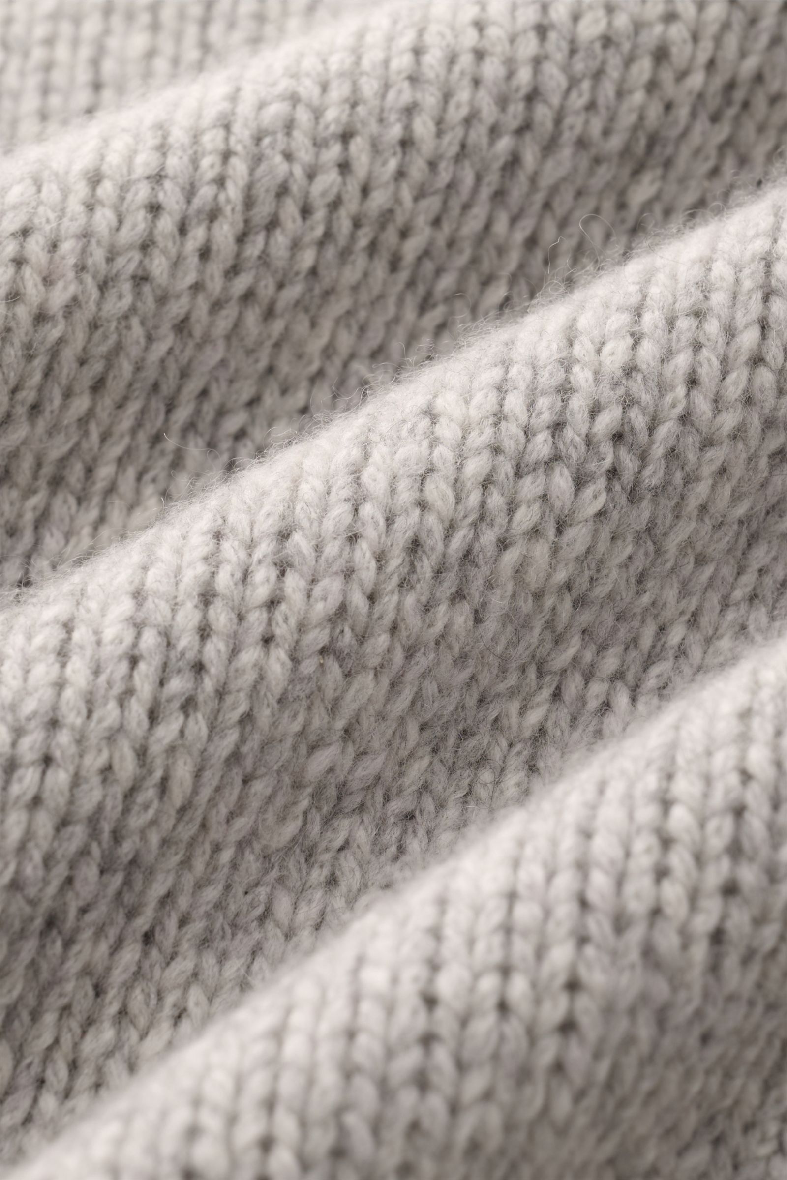 Nahaufnahme des grob gestrickten Materials des 04651/ A trip in a bag Cashmere Rollkragenpullovers hellgrau meliert aus reinem Cashmere.