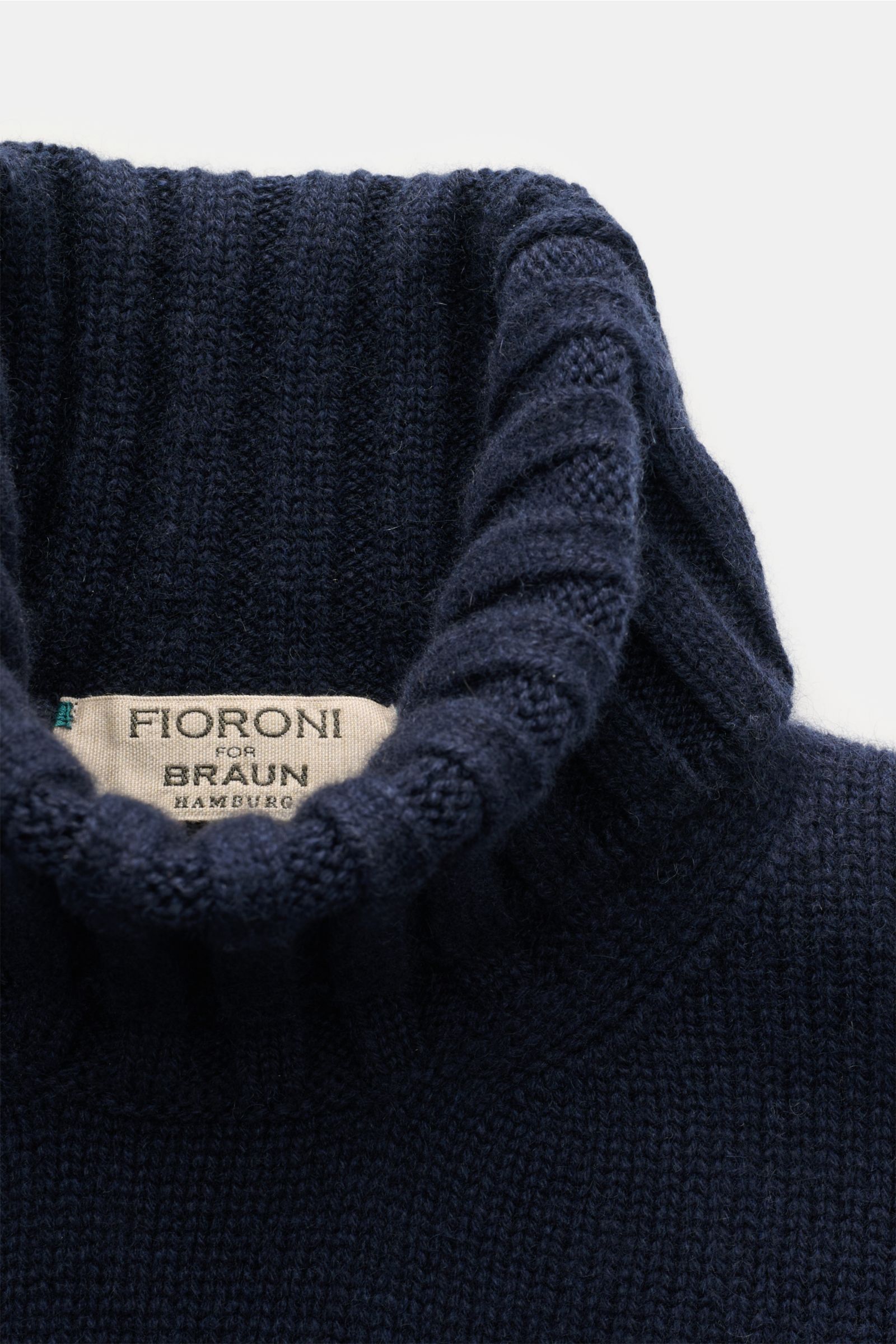 Close-up top-down view of Fioroni Cashmere Rundhalspullover navy showcasing its soft, ribbed slim-fit turtleneck collar.

Souveräne Eleganz in ihrer luxuriösesten Form: Der Rollkragenpullover von FIORONI aus erlesenem Cashmere vereint meisterhafte ital