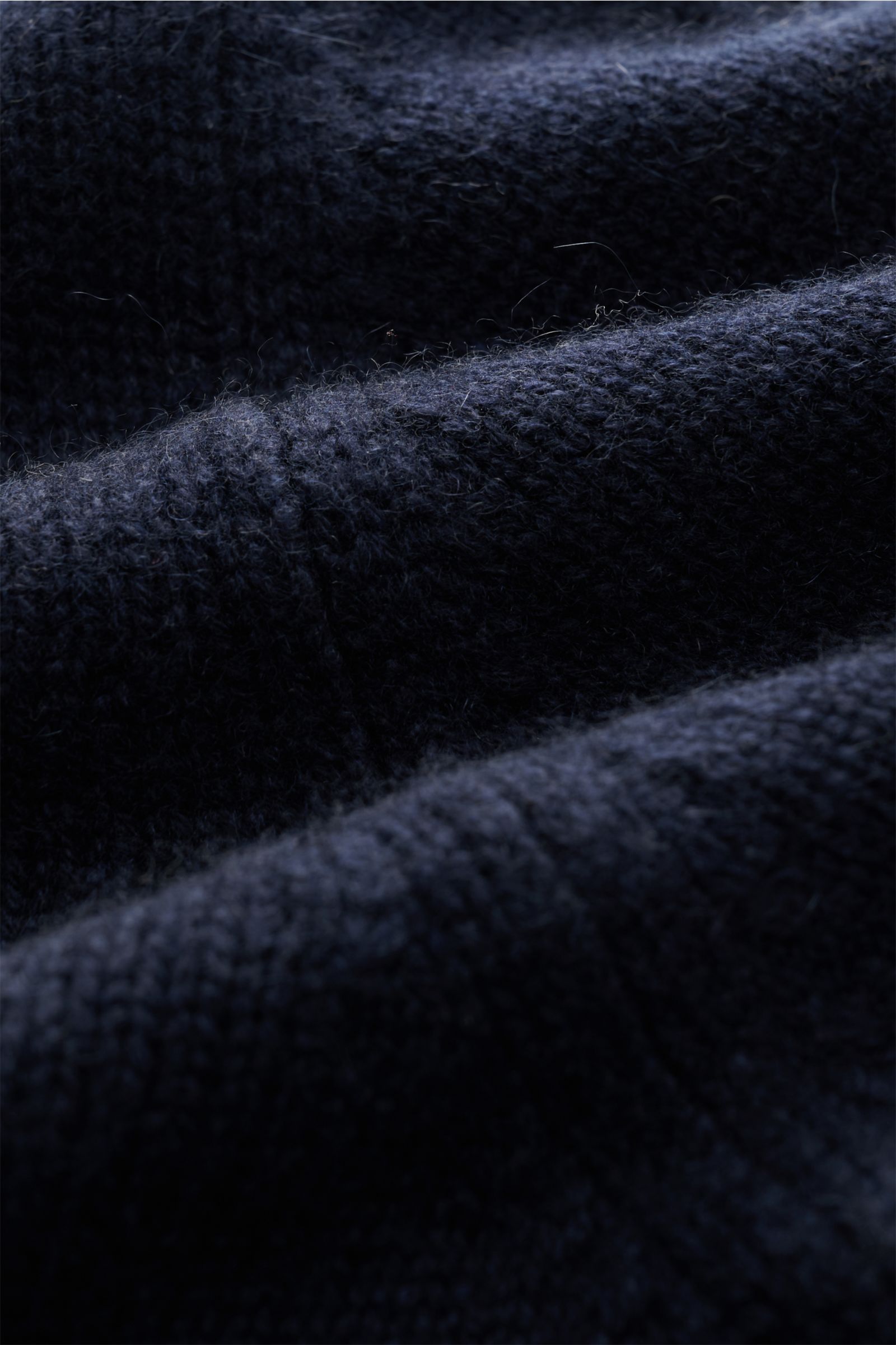 Close-up fabric detail of Fioroni Cashmere Rundhalspullover navy showing soft, finely knitted pure cashmere texture, photographed from an angled perspective. Souveräne Eleganz in ihrer luxuriösesten Form: Der Rollkragenpullover von FIORONI aus erlesene