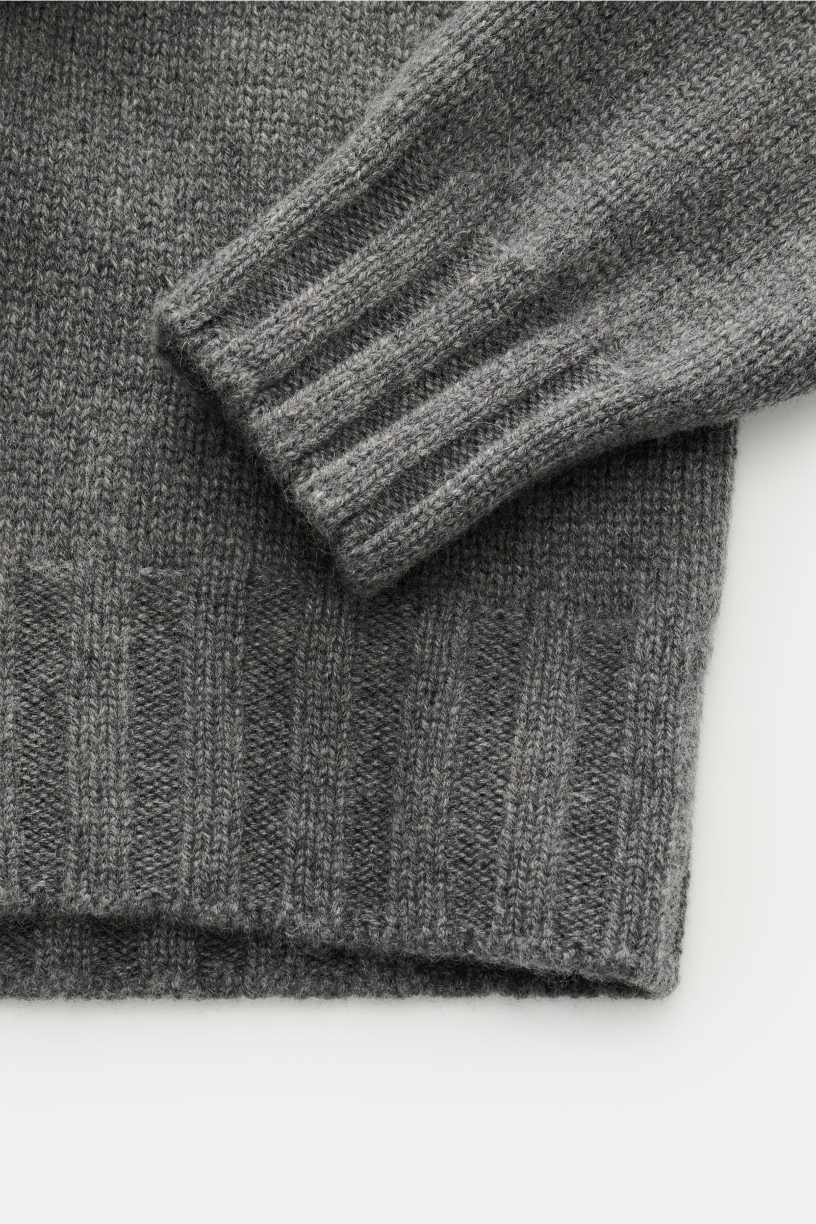 Close-up from above showing the cuff and hem of the Fioroni Cashmere Rundhalspullover dunkelgrau meliert, highlighting its mid-fine knit and soft texture. Souveräne Eleganz in ihrer luxuriösesten Form: Der Rollkragenpullover von FIORONI aus erlesenem Cash