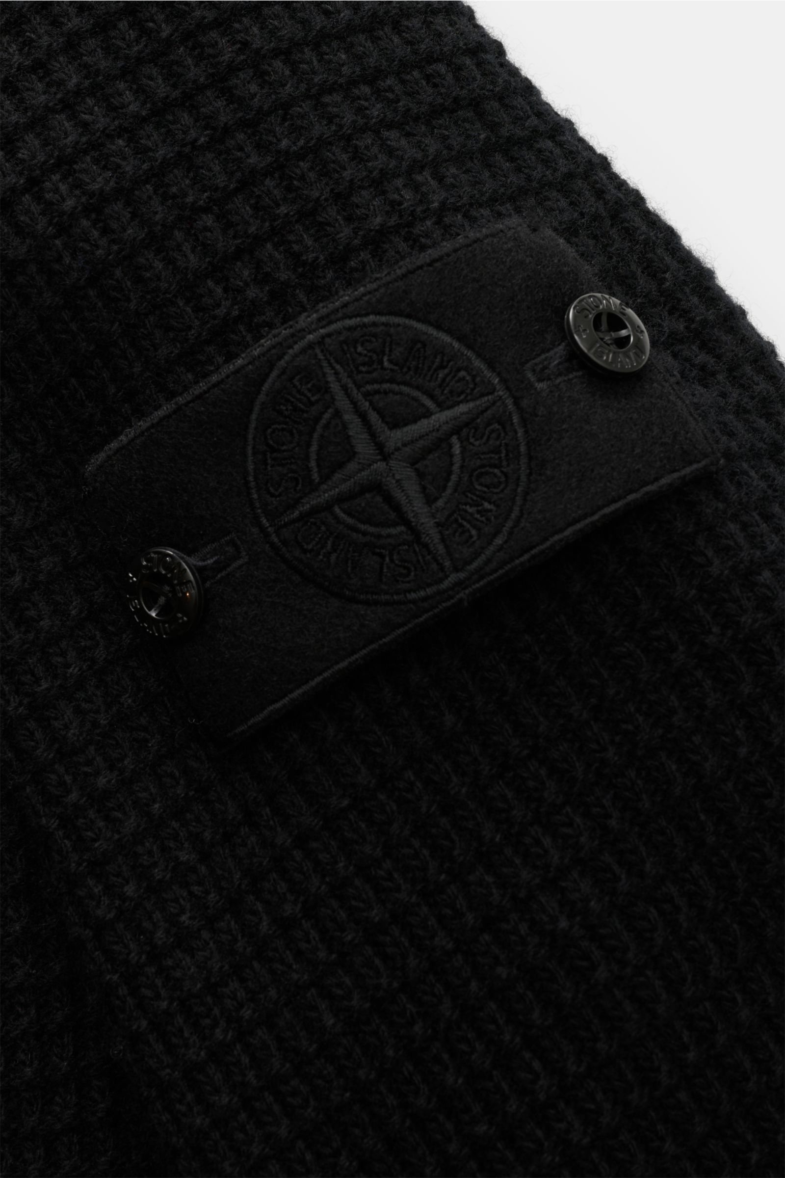 Close-up view of the textured knit and compass badge on the sleeve of the Stone Island Crew neck jumper 'Ghost' black.

Description:  
A versatile winter essential: This crew neck jumper from the 'Ghost' capsule collection by STONE ISLAND is a highly v