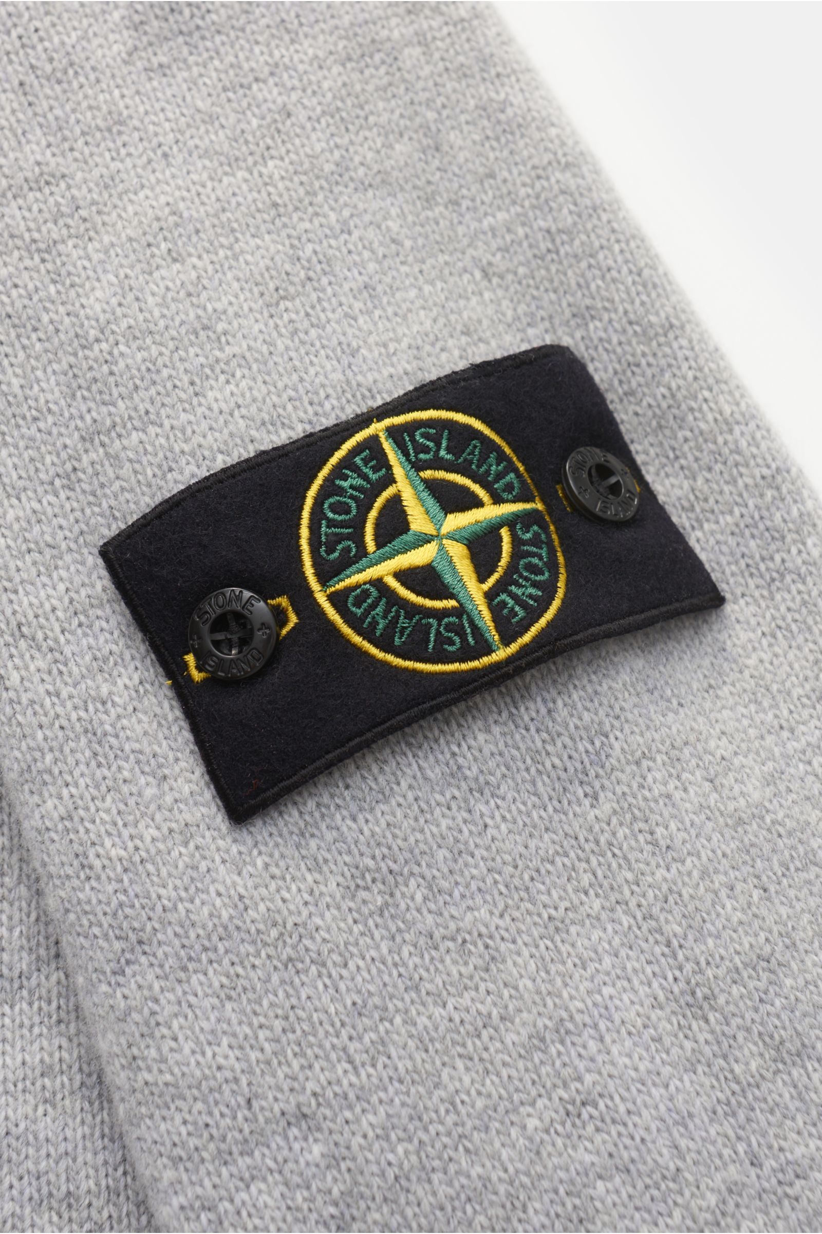 Stone Island Crew neck jumper 'Lambswool' light grey shown close-up from an angled side view, highlighting the signature compass badge on the upper sleeve made of knitwear in wool and microfibre with a soft feel, medium-fine knit, contrasting knit stripes