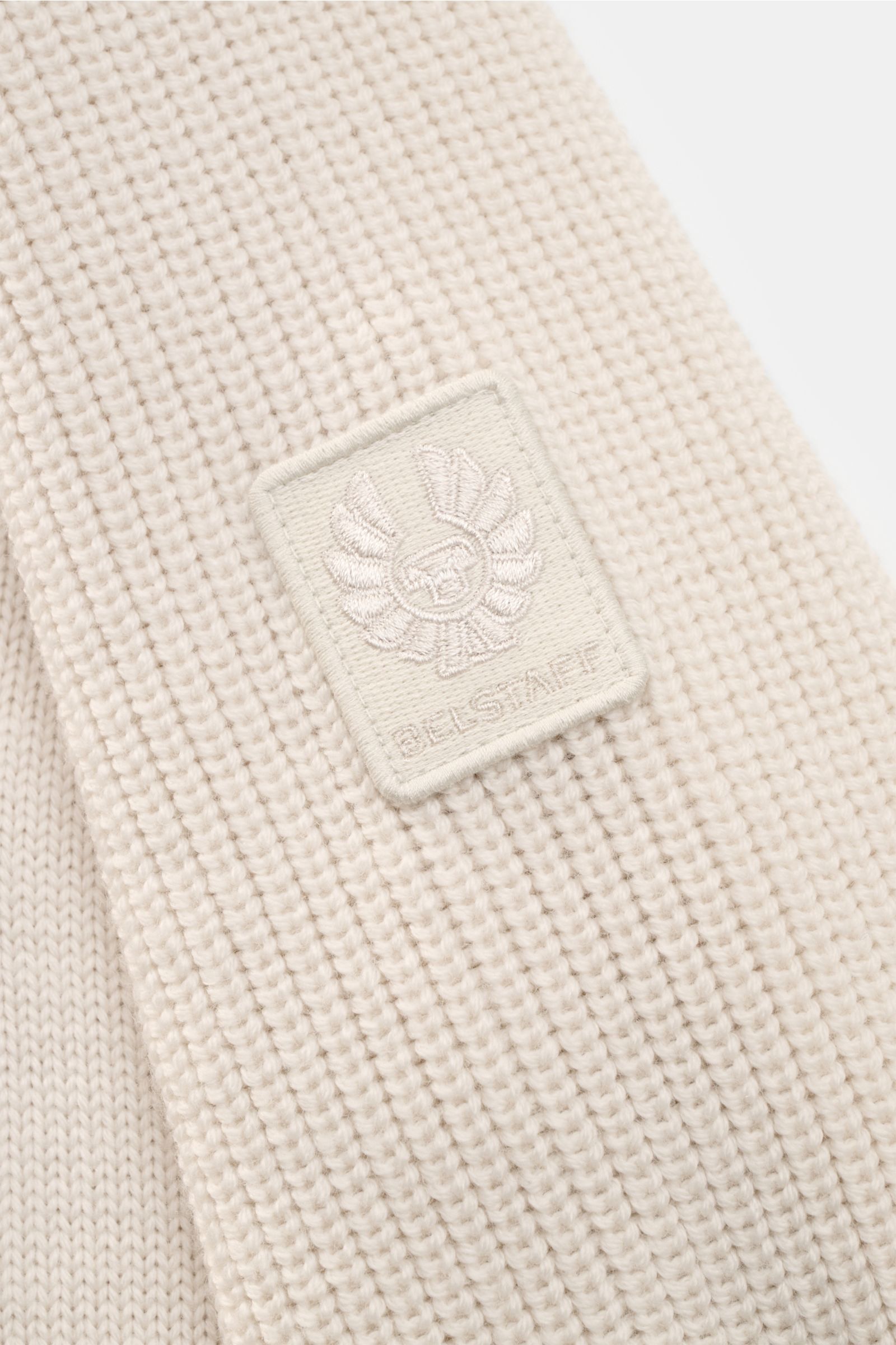 Close-up of the Belstaff Rundhalspullover 'Aspect' sand showing the soft, mid-fine knit wool texture and BELSTAFF logo patch on the upper arm, photographed from a side angle. Vielseitiger Klassiker für Herbst und Winter: Der Rundhalspullover von BELSTAFF 