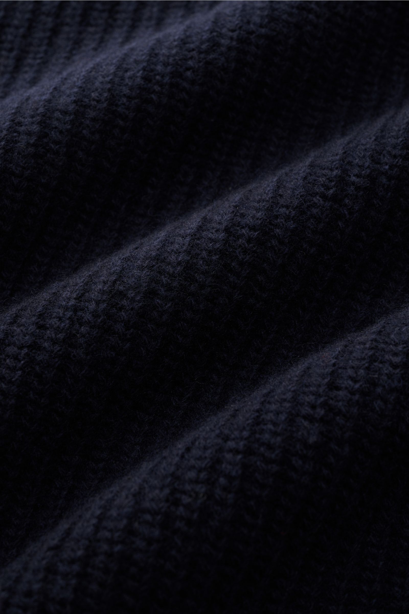 Close-up from a slightly angled perspective of the ribbed navy wool fabric of the Closed Rundhalspullover navy, showcasing its coarse rib knit texture and soft feel.

Description: Wandelbarer Klassiker vom Hamburger Label CLOSED: Reine Wolle, markantes