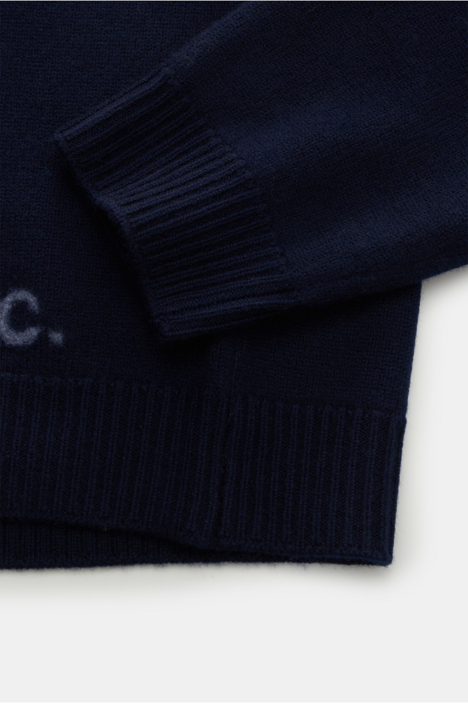 Close-up front view of the A.P.C. Rundhalspullover 'Edward' navy showing the cuff and hem with reine Wolle, weicher Griff, mittelfeines Strickbild, Slim Fit, flexible Rippbündchen, and a dezentes Logo auf der Vorderseite.