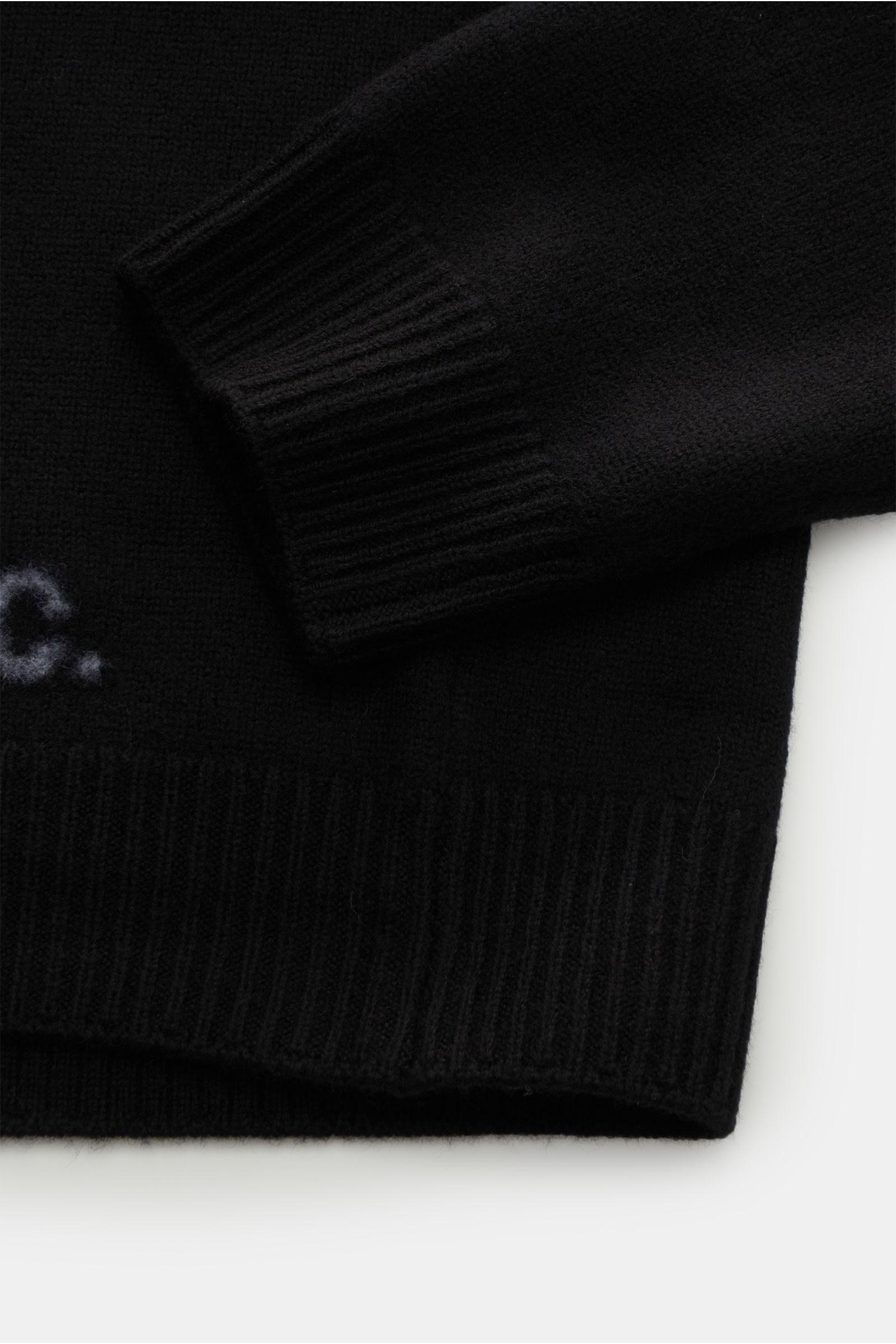Close-up front-side view of A.P.C. Rundhalspullover 'Edward' schwarz showing slim fit black sweater with reine Wolle, weicher Griff, mittelfeines Strickbild, flexible Rippbündchen, and a discreet logo on the front.