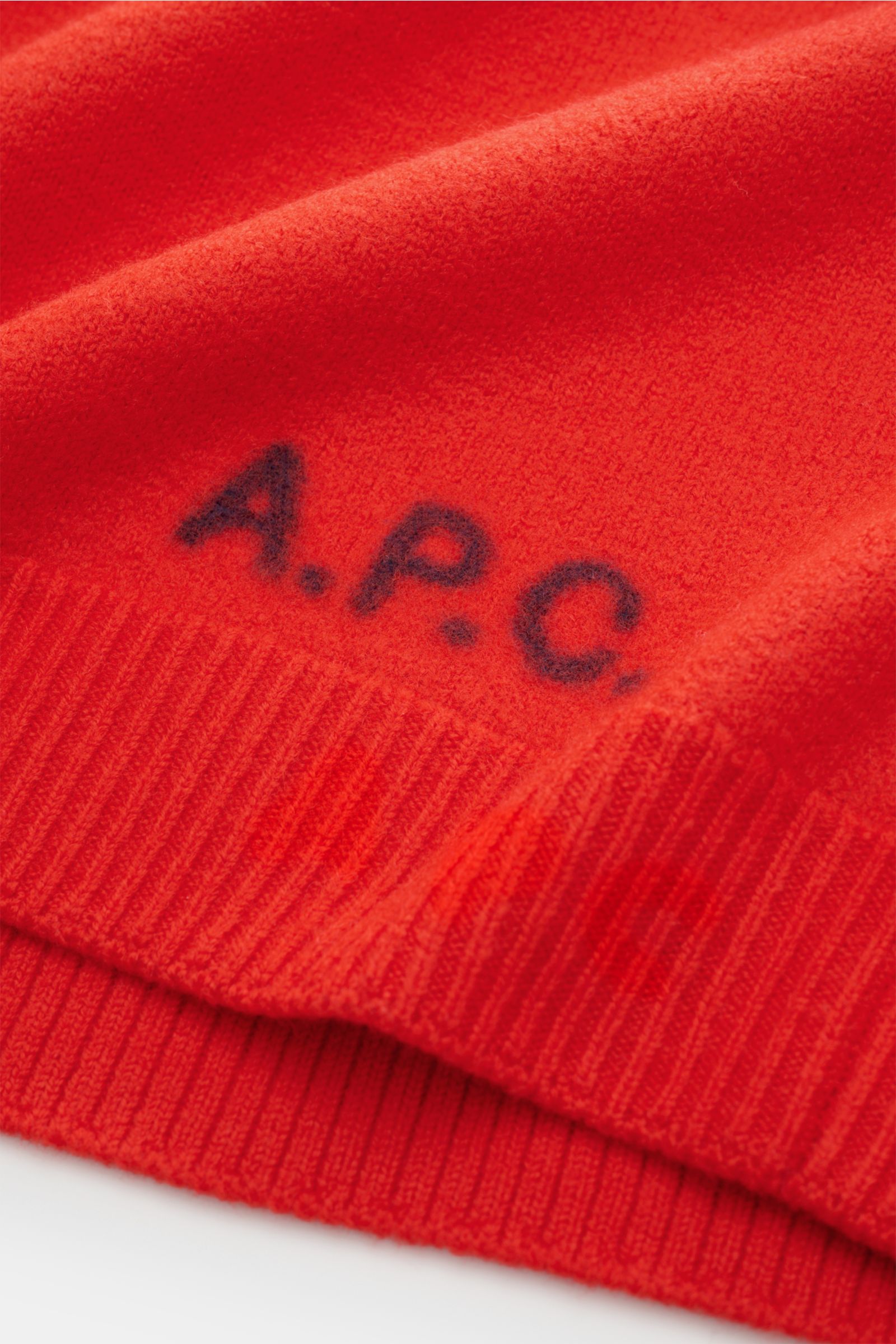 Close-up front view of the A.P.C. Rundhalspullover 'Edward' hellrot, showing pure new wool fabric, felted quality, soft compact feel, medium-fine knit, slim fit, flexible rib cuffs, and front logo.