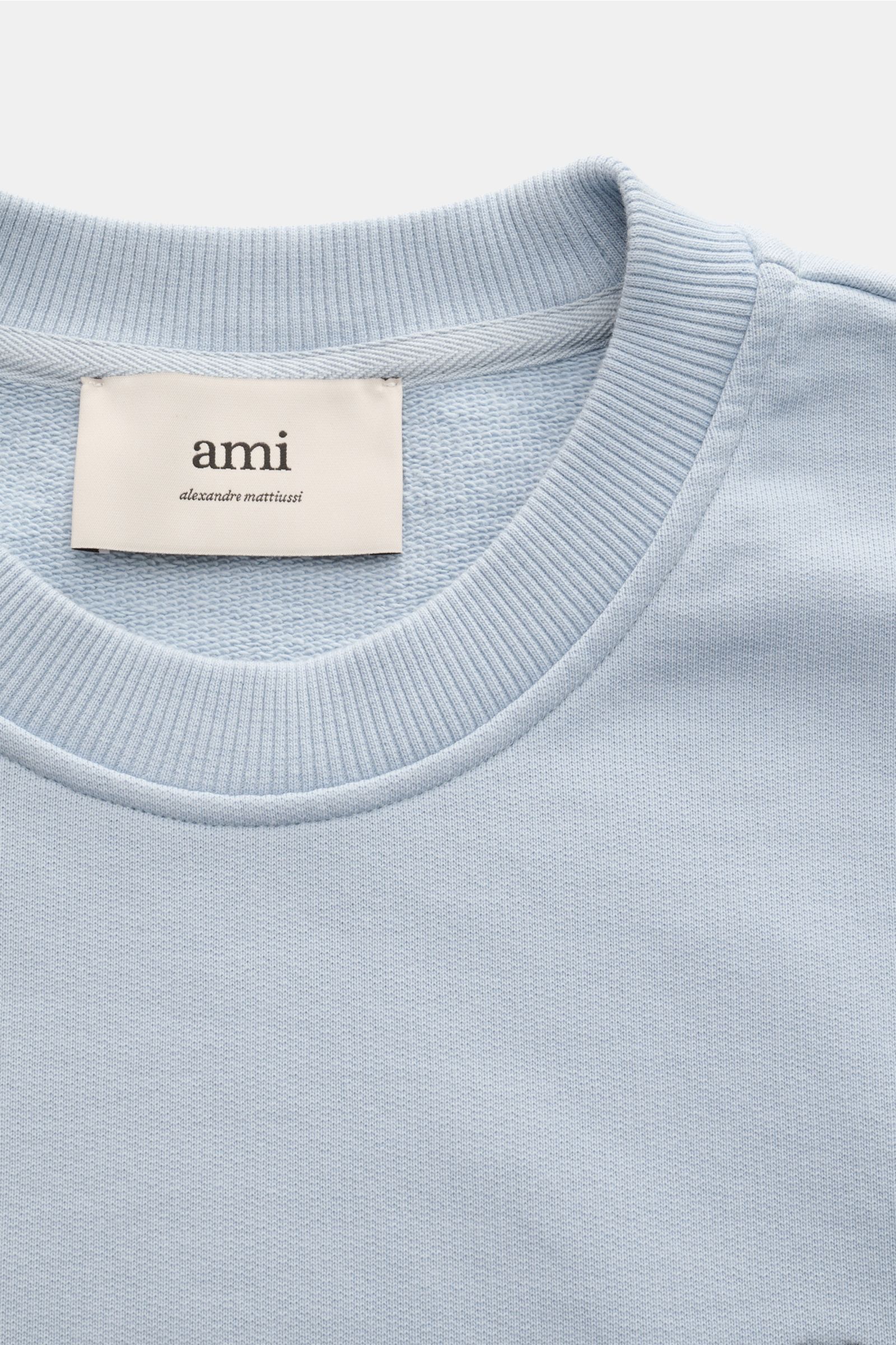 Ami Paris Rundhals-Sweatshirt hellblau shown from a close-up top front view highlighting the ribbed round neckline and soft light blue cotton fabric with a subtle texture. Ein dezentes Herz-Stitching auf der Brust wertet dieses Basic-Sweatshirt aus Bau