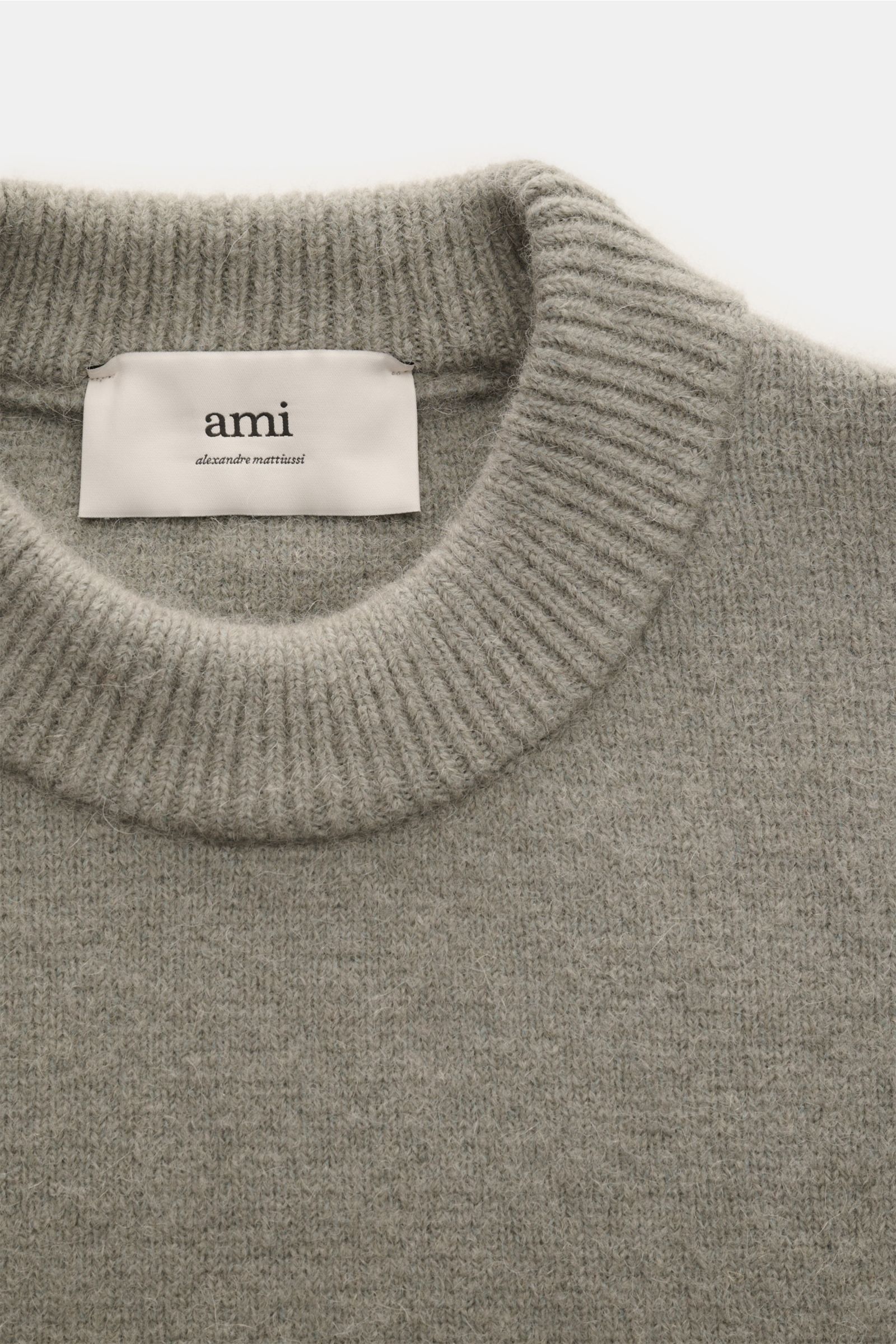 Close-up front view of the Ami Paris Rundhalspullover grau, a gray unisex round-neck sweater made of elastic alpaca, wool, and microfiber knit with soft texture and ribbed collar. Legerer Luxus für kalte Tage: AMI PARIS interpretiert seinen ikonischen Pul