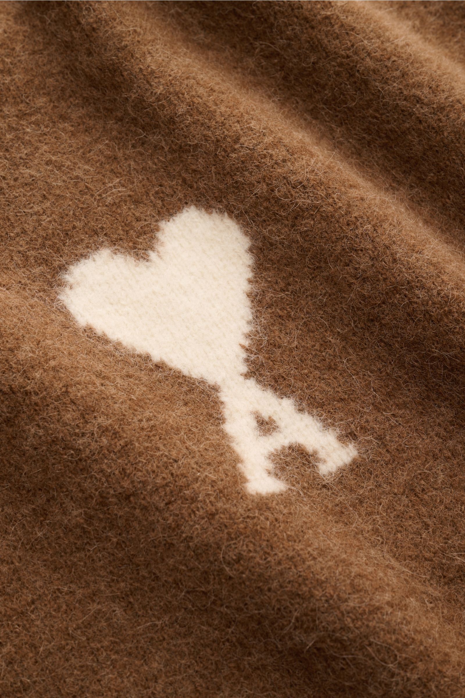 Ami Paris Rundhalspullover hellbraun, Detailansicht des weichen, voluminösen Alpaka-Stricks mit weißem Herz-Logo, perspektivisch nah.